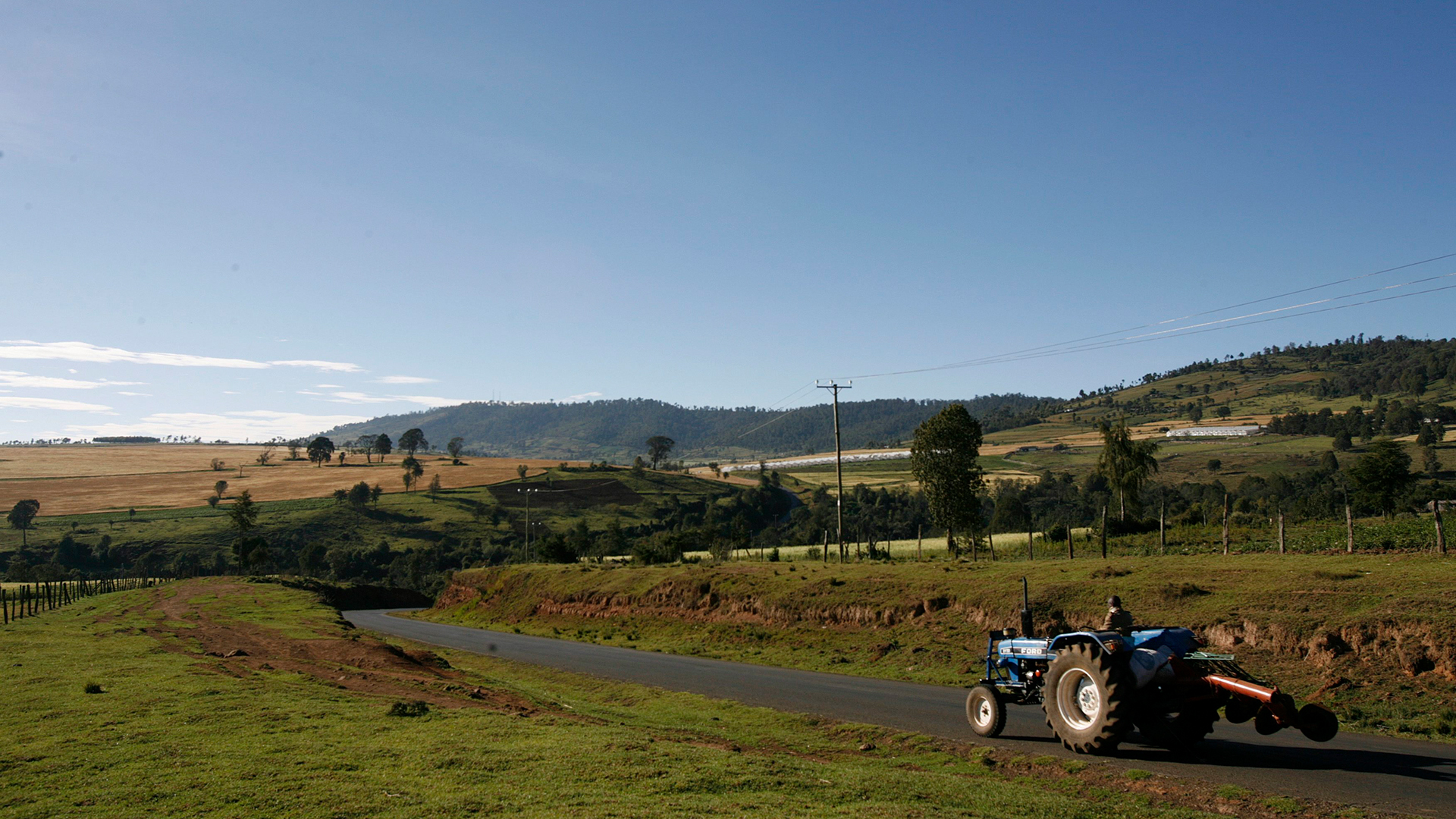 Ein Landwirt fährt auf einem Traktor durch Felder am Rande der Stadt Mau Narok in Kenia.  | picture alliance / dpa