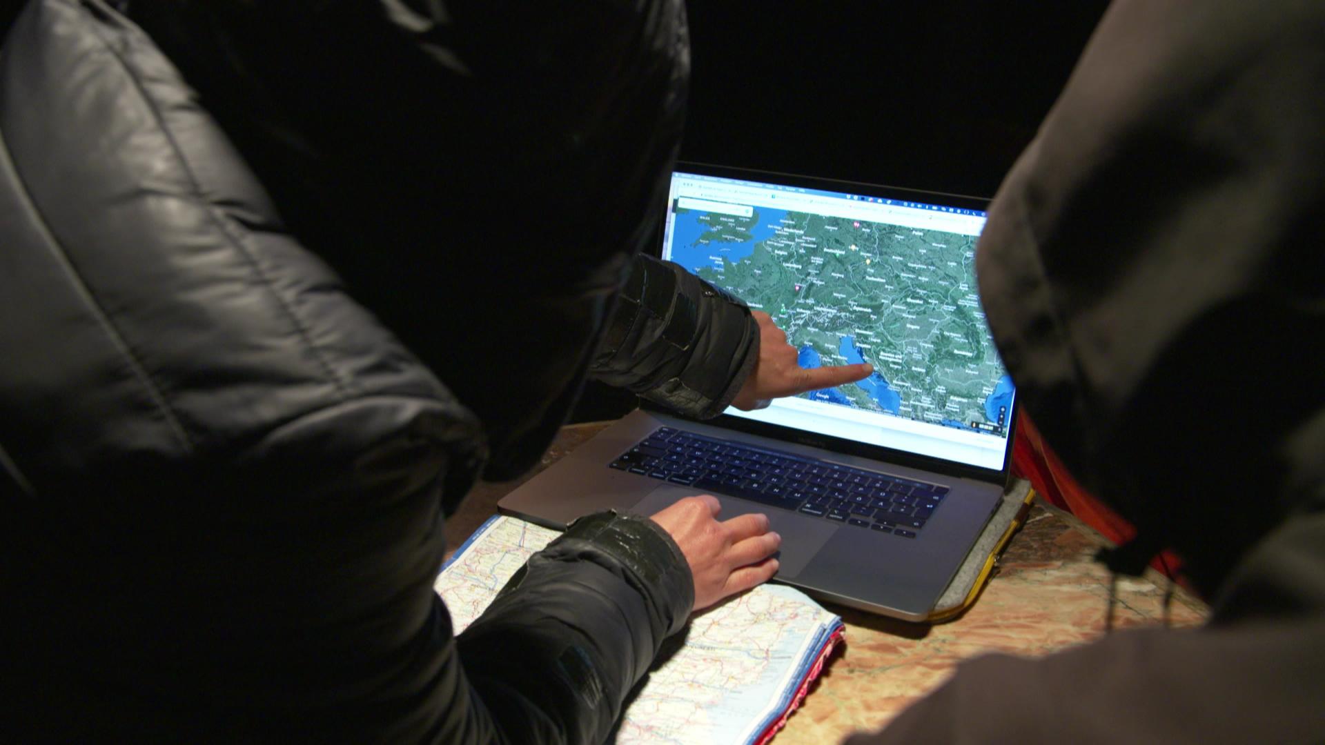 Zwei Personen vor einem Laptop, auf dem eine Karte zu sehen ist - eine zeigt mit dem Finger auf den Monitor. | Screenshot Report Mainz