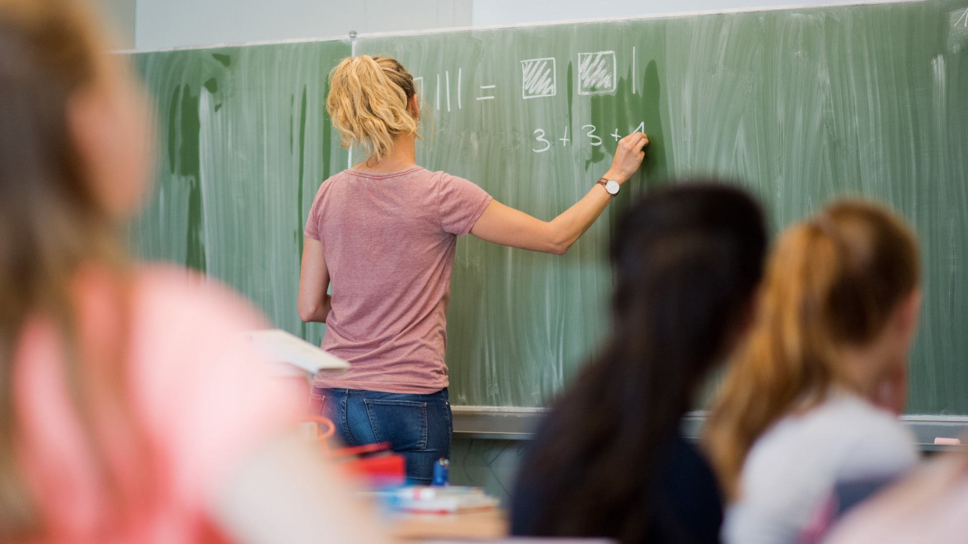 Eine junge Lehrerin schreibt Zahlen auf eine Tafel  | Bildquelle: dpa