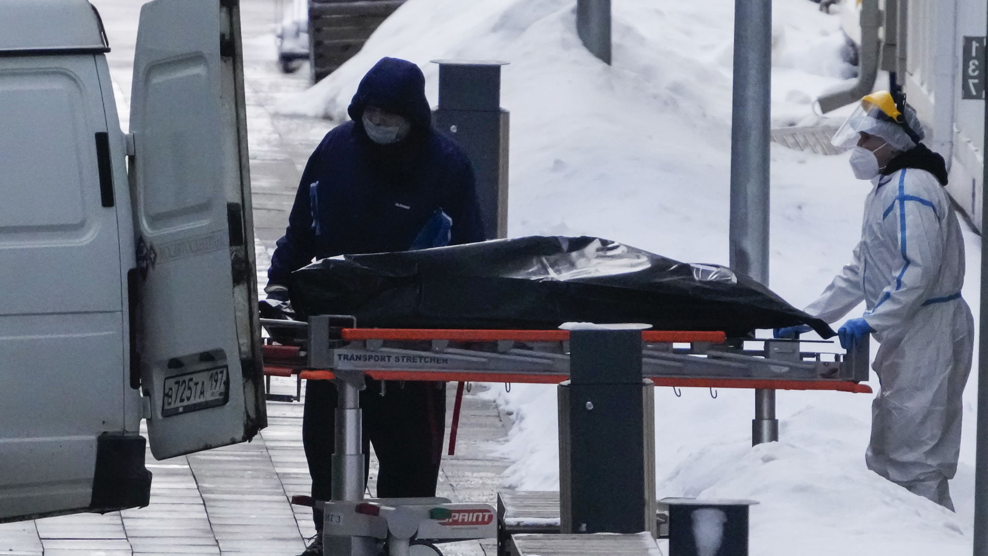 Medizinisches Personal schiebt eine Leiche aus einem Krankenhaus in Moskau zu einem Fahrzeug.