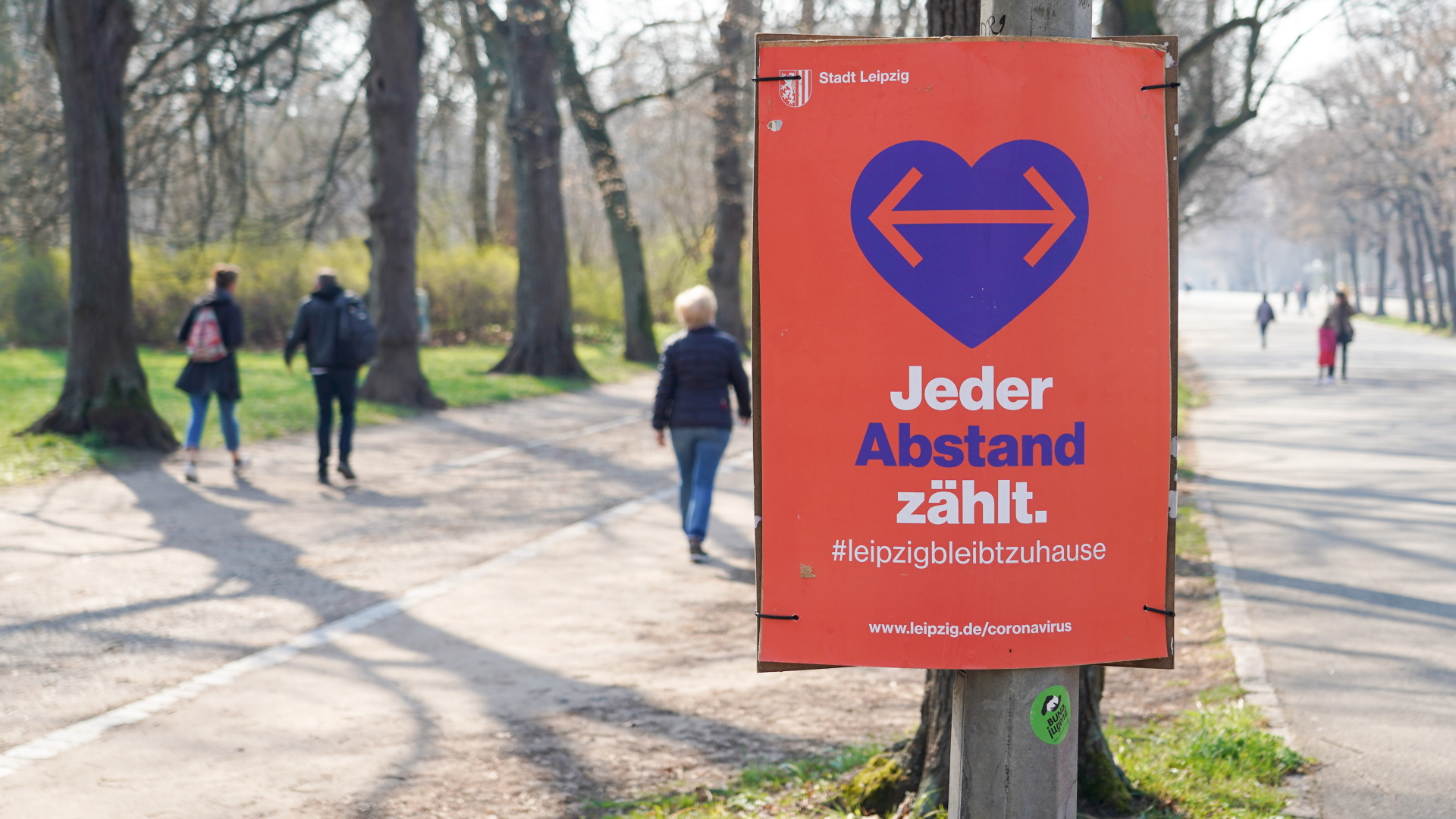 Ein Plakat mit der Aufschrift "Jeder Abstand zählt" hängt im Clara-Zetkin-Park in Leipzig. | dpa