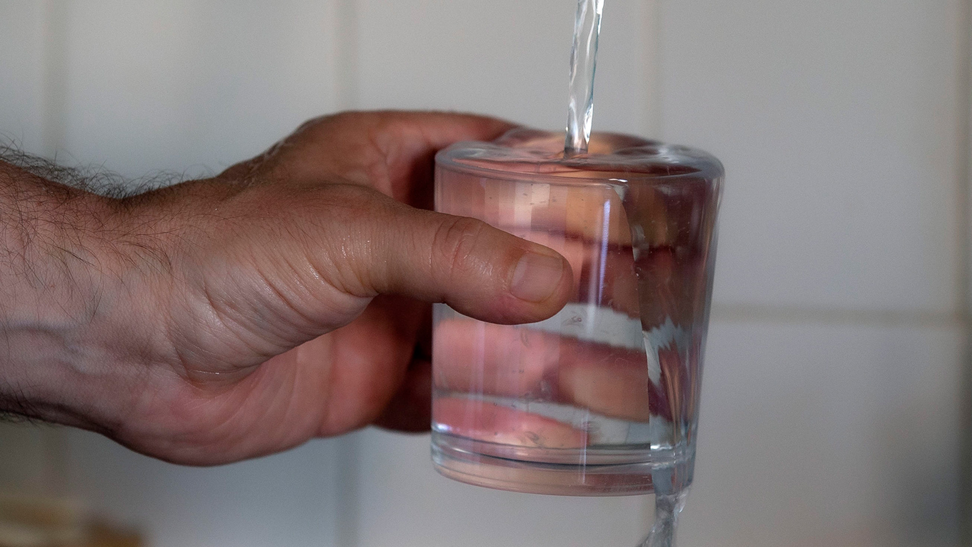 Ein Mann befüllt ein Glas mit Wasser aus der Leitung. | EPA
