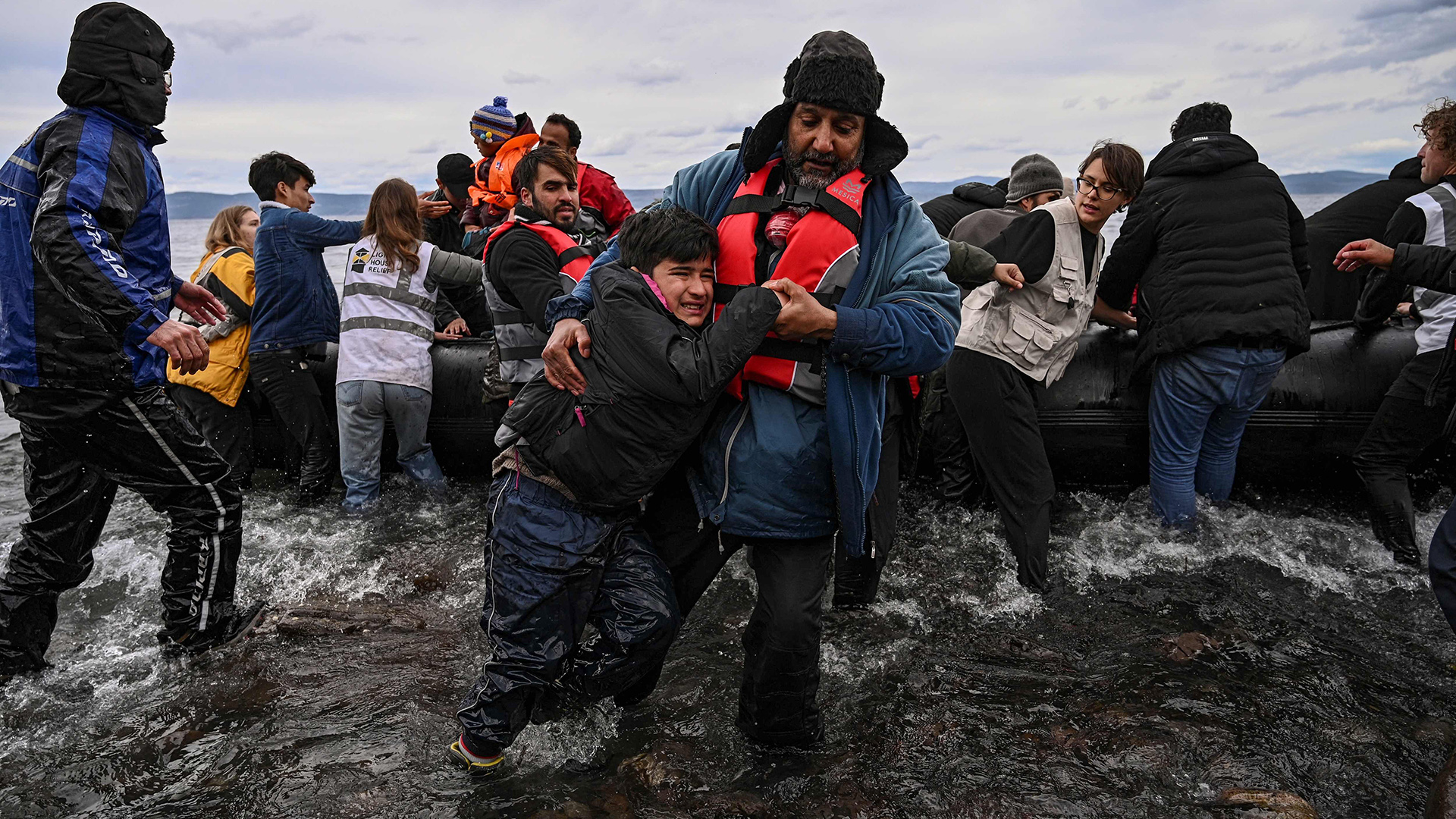 Ein Mann hilft einem Jungen beim verlassen eines Schlauchbootes, Lesbos/Griechenland. | AFP