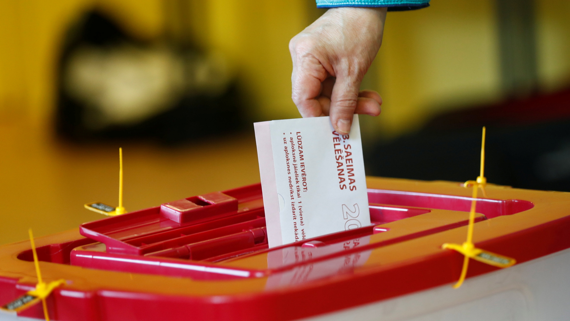 Bei der Wahl in Lettland wirft ein Mensch einen Wahlzettel in eine Wahlurne | Bildquelle: REUTERS