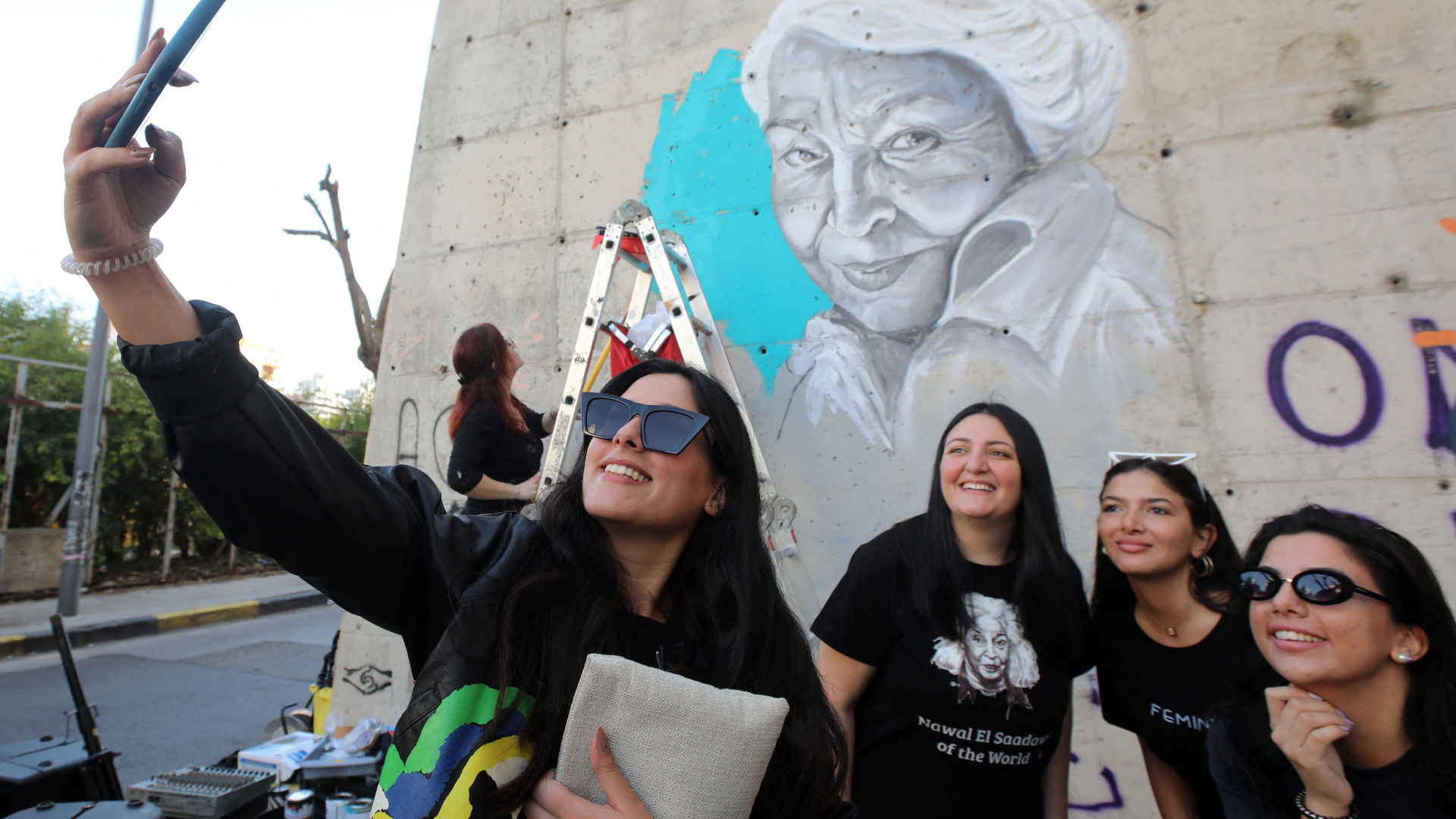 Vier junge Libanesinnen fotografieren sich vor einem Wandbild der ägyptischen Feministin und Autorin Nawal el-Saadawi