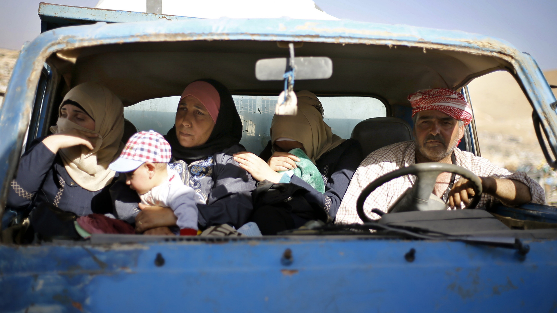 Eine syrische Familie sitzt in einem alten Auto mit zerschlagener Windschutzscheibe.