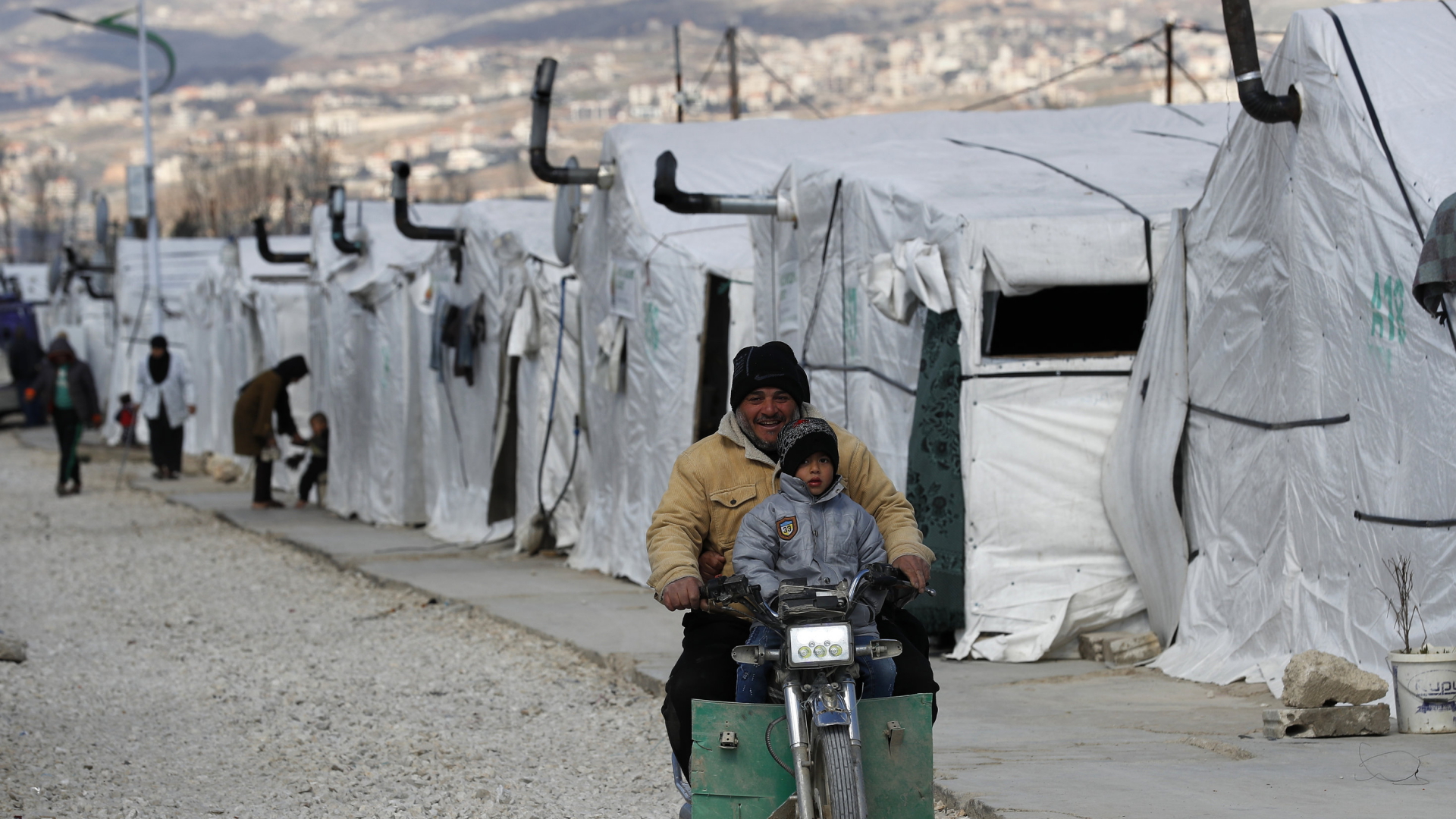 Im Bekaa-Tal (Libanon) fahren Flüchtlinge aus Syrien auf einem Motorroller durch eine Flüchtlingslager | AP