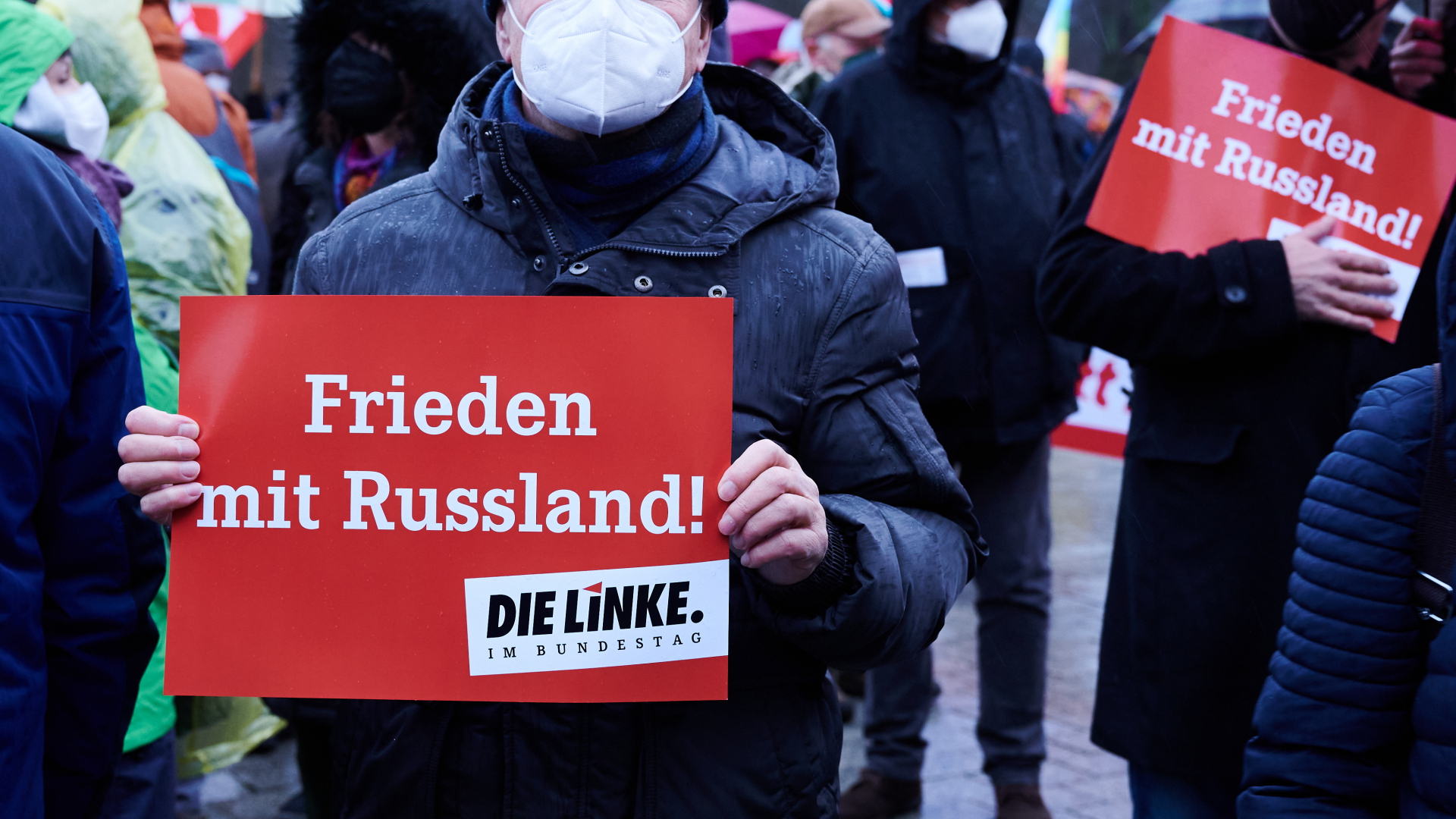 Ein Demonstrant in Berlin hält ein Plakat mit der Aufschrift "Frieden mit Russland - Die Linke im Bundestag" in den Händen. | dpa