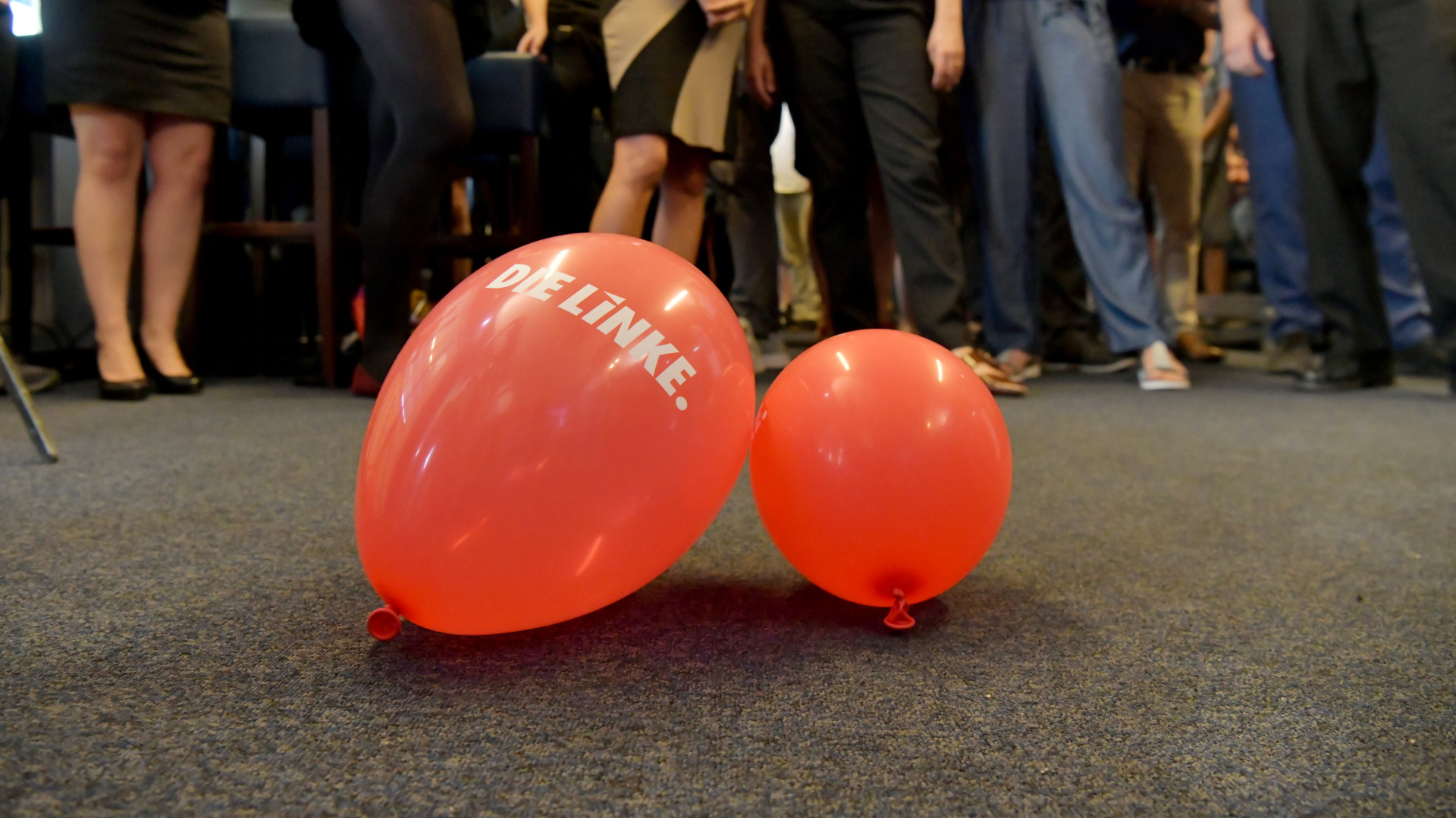 Zwei Luftballons mit dem Schriftzug "Die Linke" liegen auf einem grauen Teppichboden. | dpa