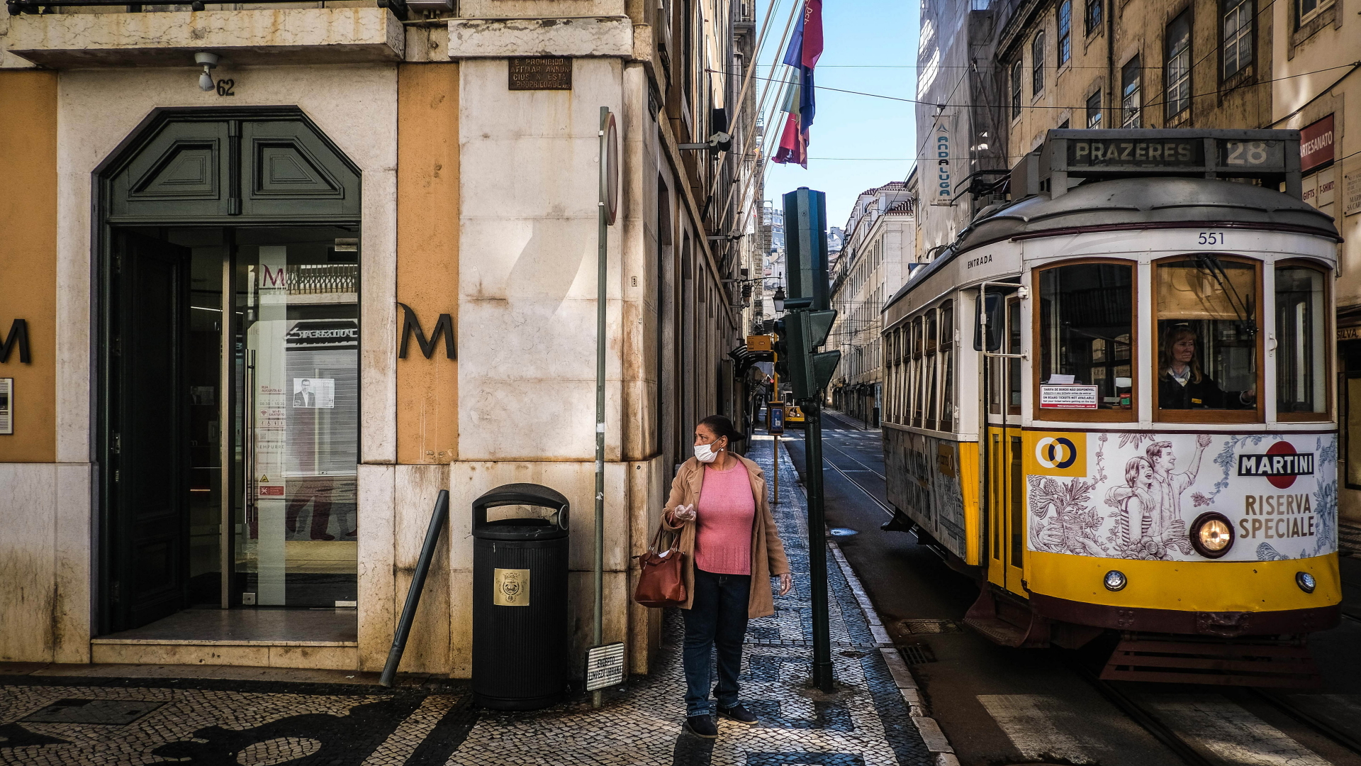 Eine Frau mit Mundschutz steht neben einer Straßenbahn in Lissabon. | MARIO CRUZ/EPA-EFE/Shutterstock