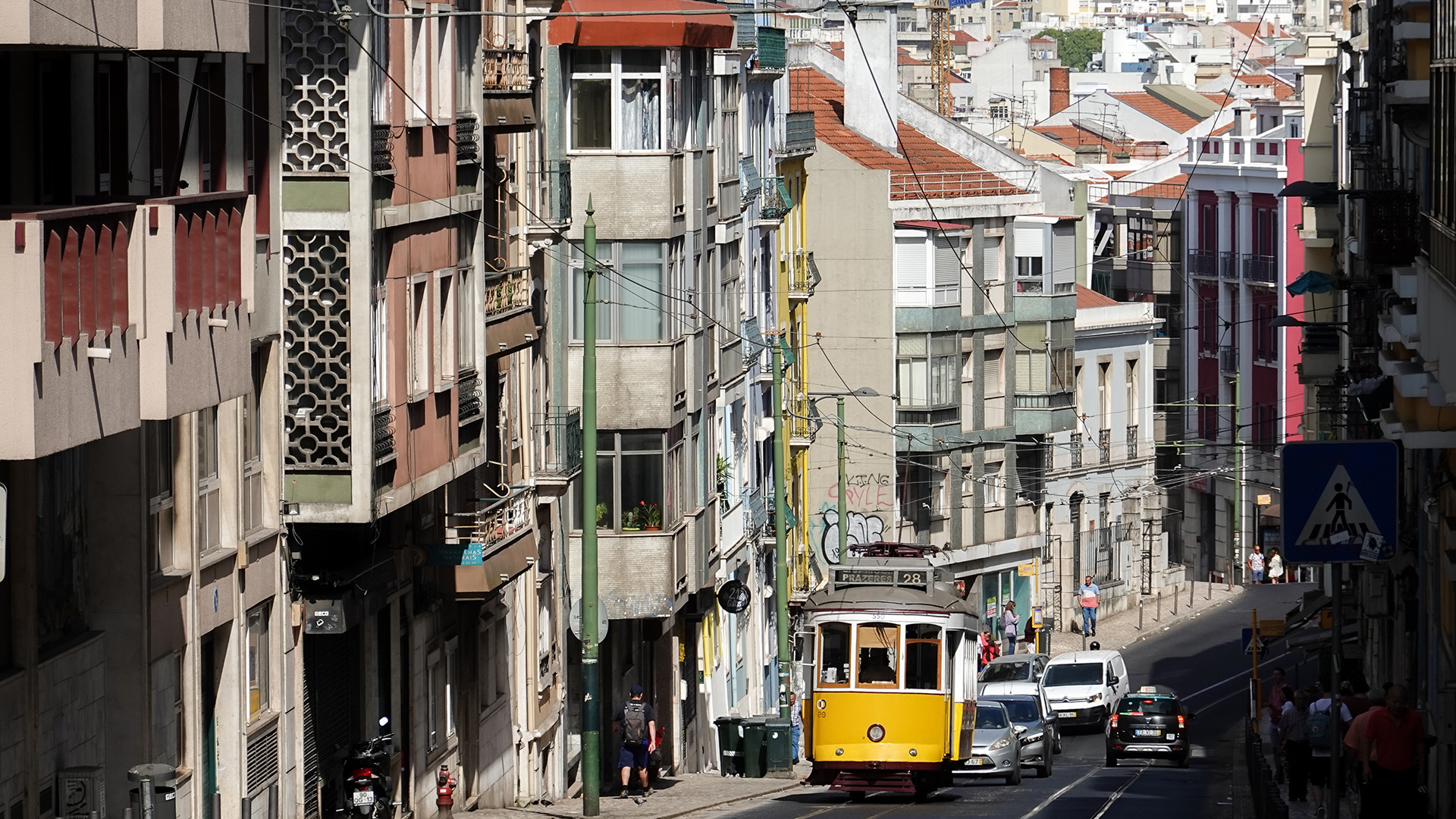 Eine Straßenbahn der Linie 28 fährt einen Berg hoch durch ein Wohnviertel in Lissabon. | dpa