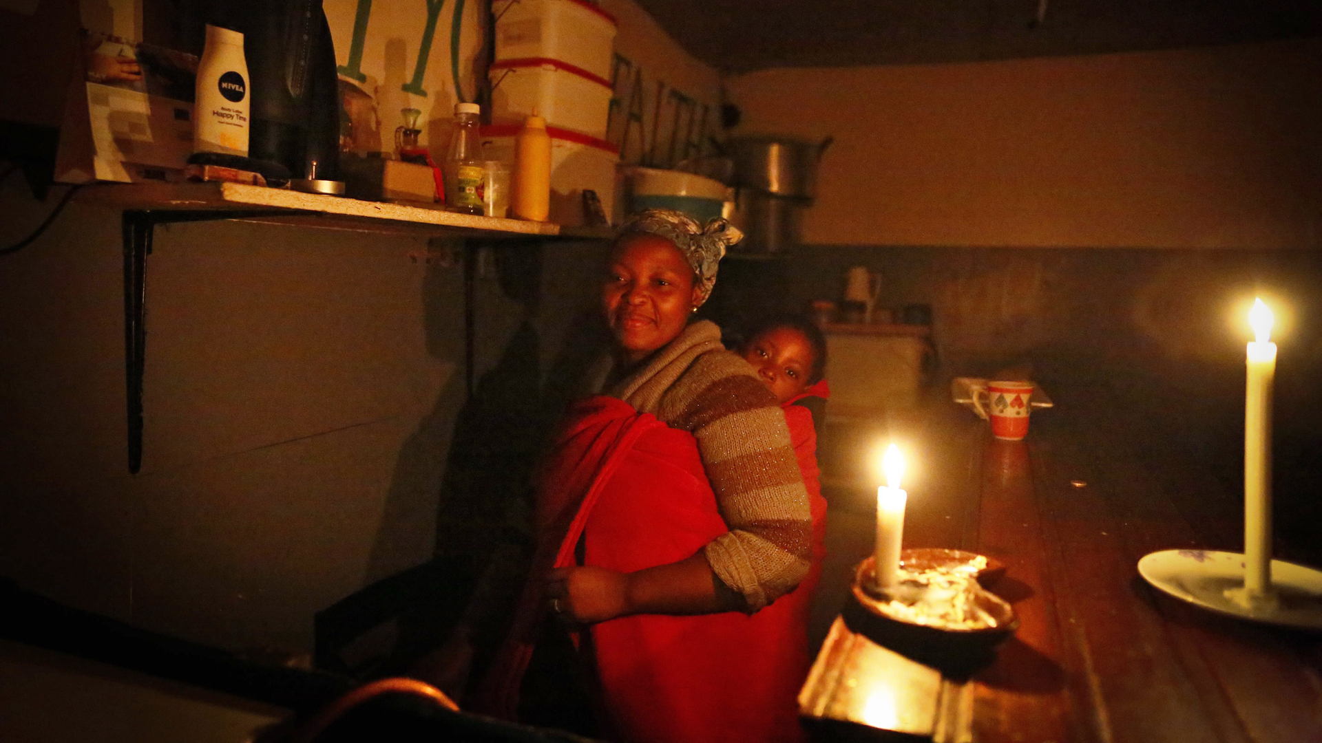 Bei Kerzenlicht: Eine Frau mit Kind, während in Kapstadt der Strom abgestellt ist. | picture alliance / dpa