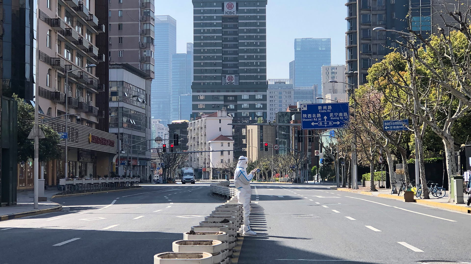 Ein Mann in einem Schutzanzug steht inmitten leerer Straßen in einem abgesperrten Gebiet im Bezirk Jingan im Westen von Shanghai.