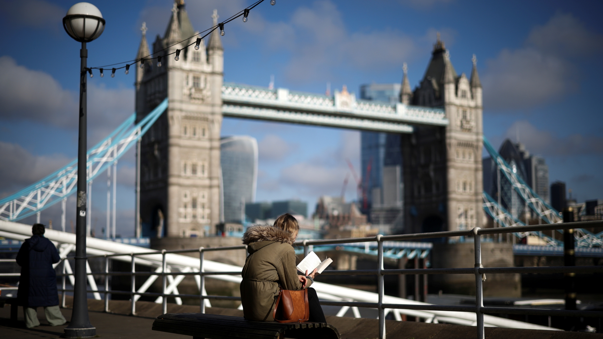 Eine Frau liest ein Buch an der Themse in London. | REUTERS