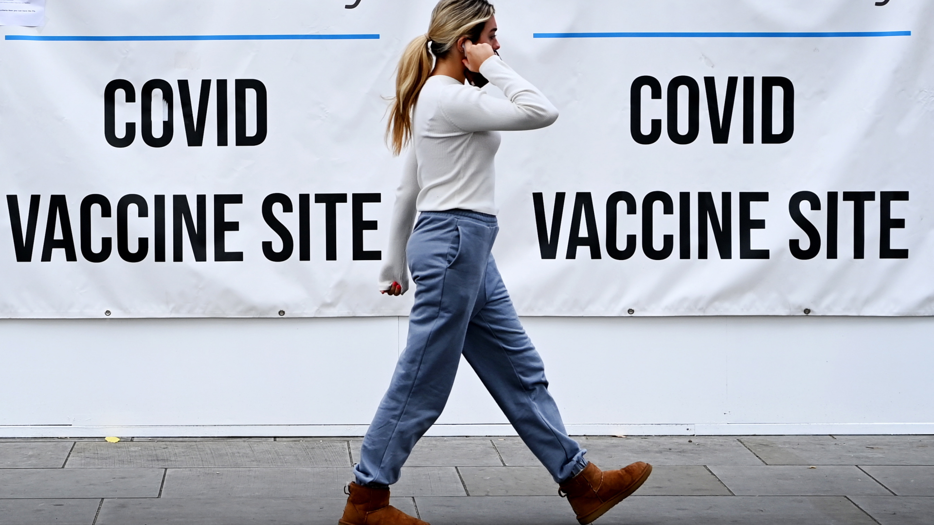Eine Frau in London geht an Hinweisschildern für die Corona-Impfung vorbei | EPA