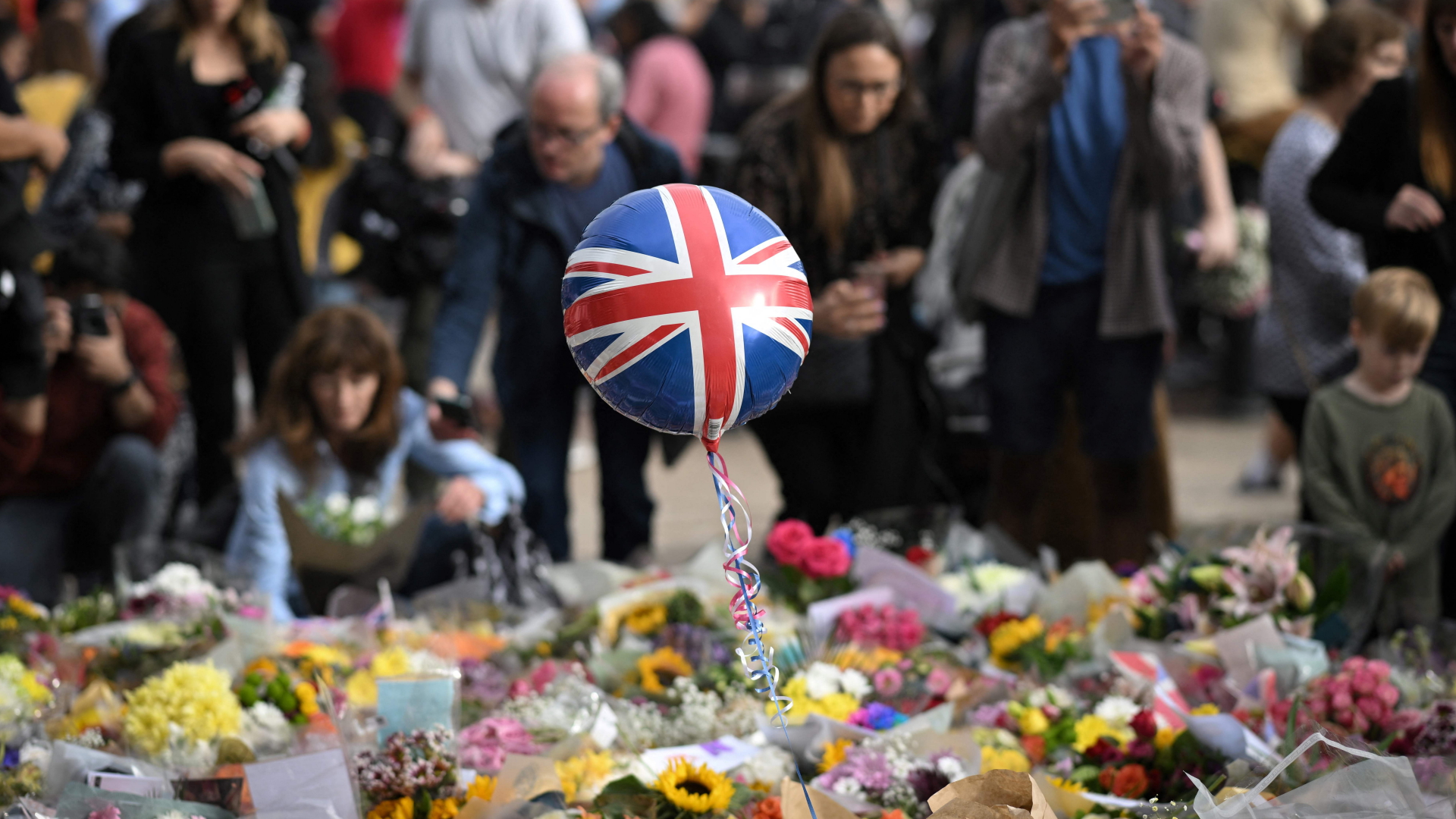 Menschen legen Blumen für die verstorbene Queen am Buckingham Palast nieder | AFP