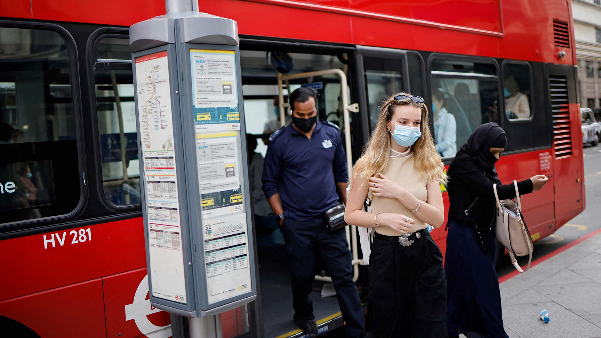 Menschen mit Schutzmasken steigen aus einem Londoner Doppeldeckerbus | AFP