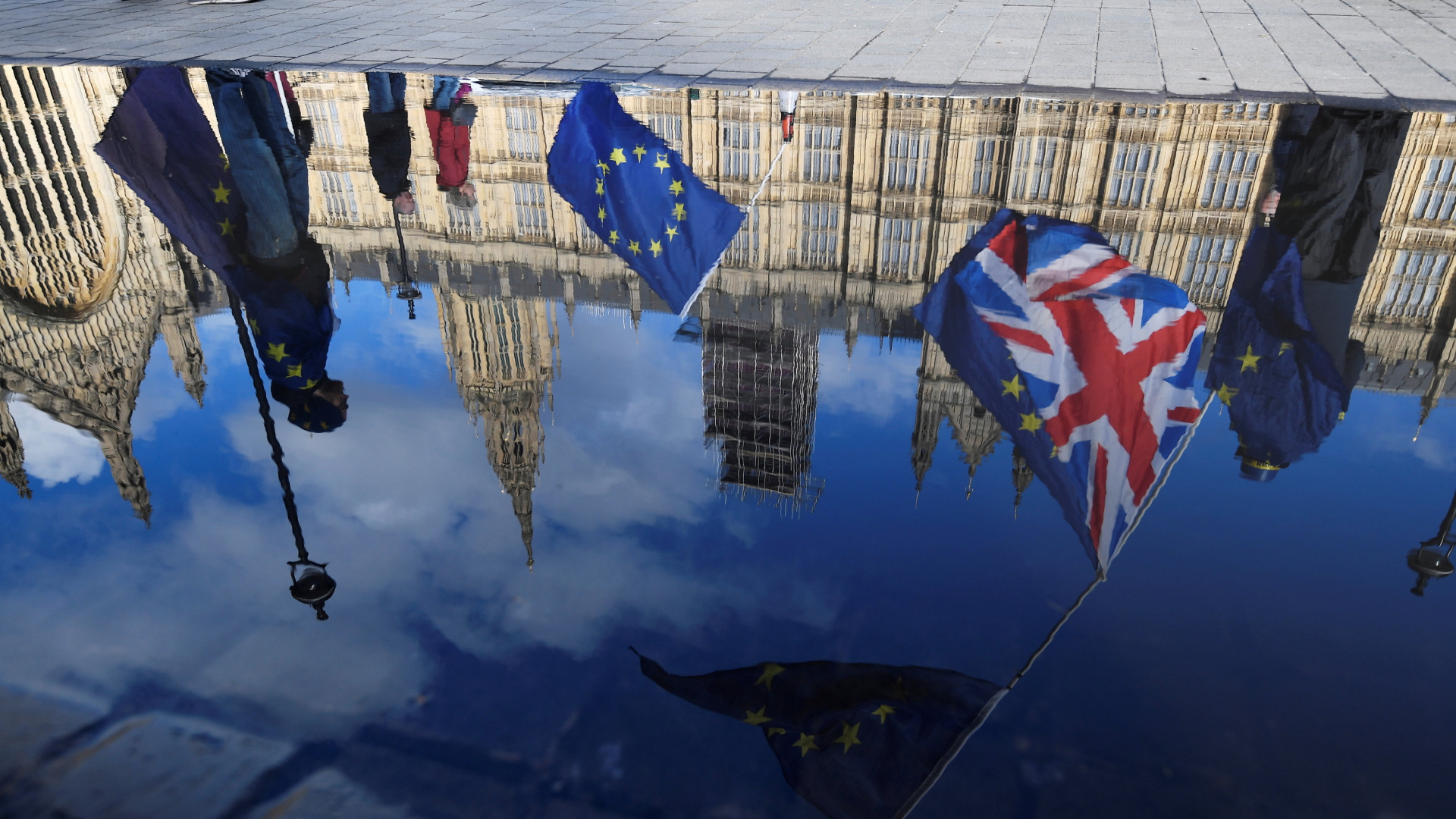 In einer Regenpfütze spiegelt sich das britische Parlament mit Europa- und Großbritannien-Flaggen im Vordergrund. | REUTERS