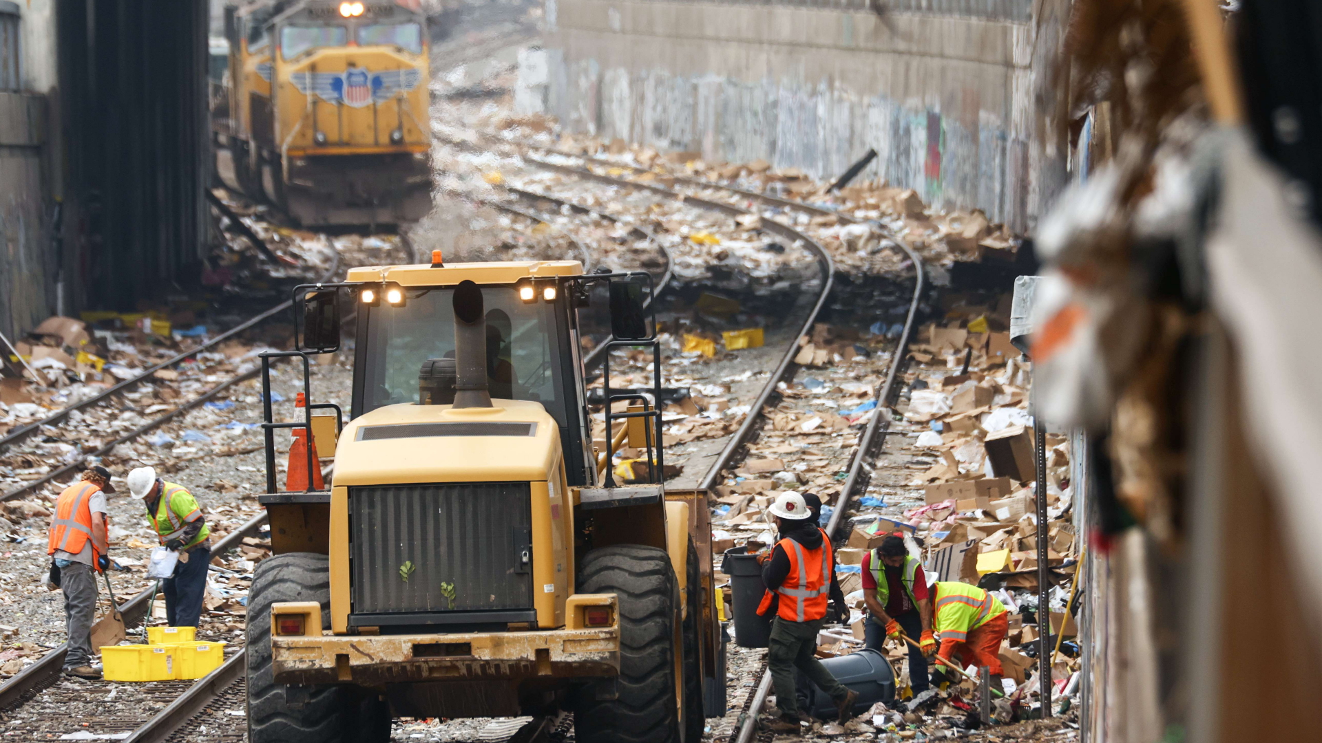 Auf Zuggleisen in Los Angeles (USA) räumen Bagger die Reste von Paketen weg, die Diebe aufgerissen und weggeworfen haben | AFP