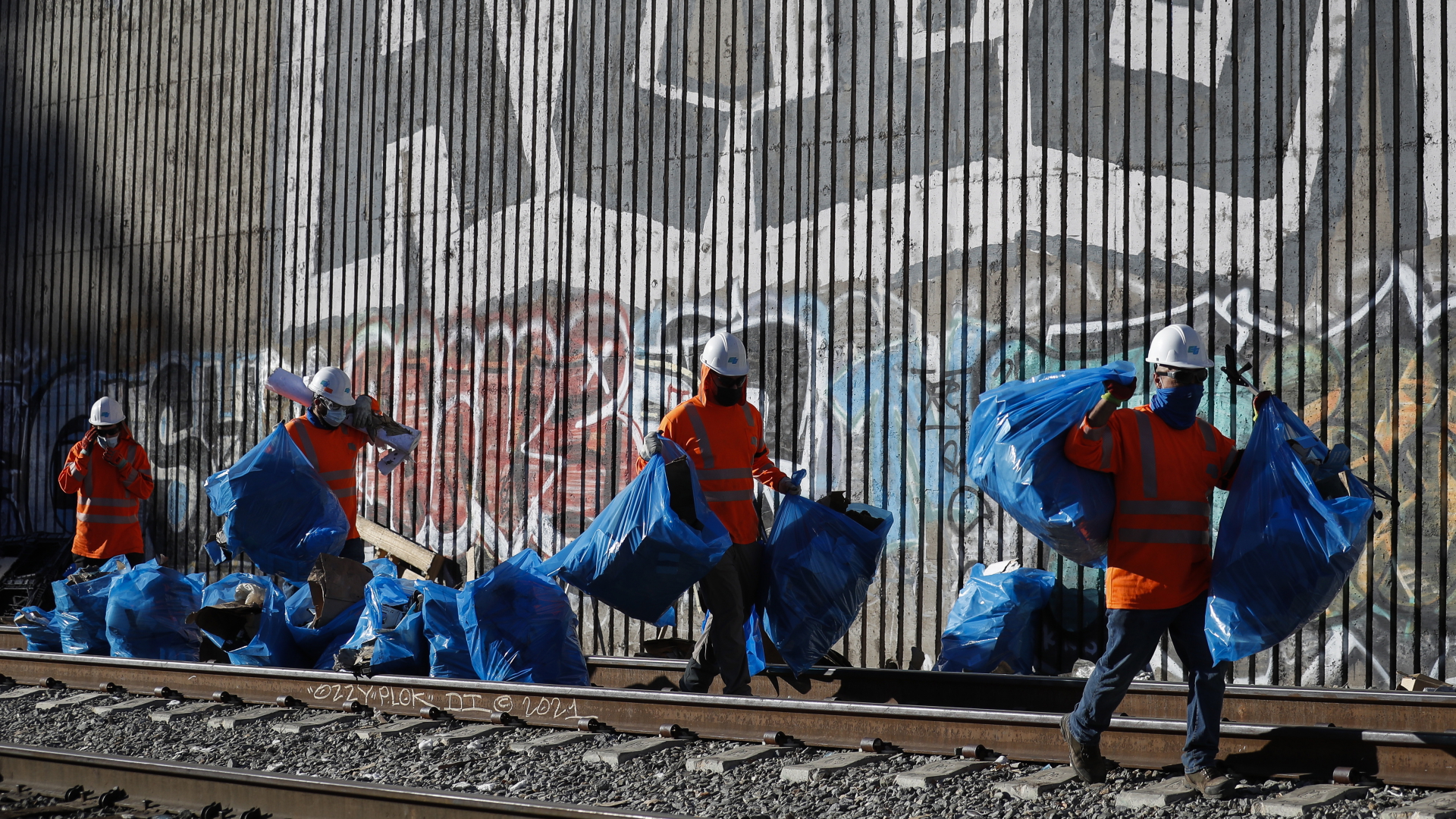 Städtische Mitarbeiter tragen in Müllsäcken die Reste von Diebesgut weg, das auf den Zügen von Los Angeles (USA) zurückgelassen wurde | EPA