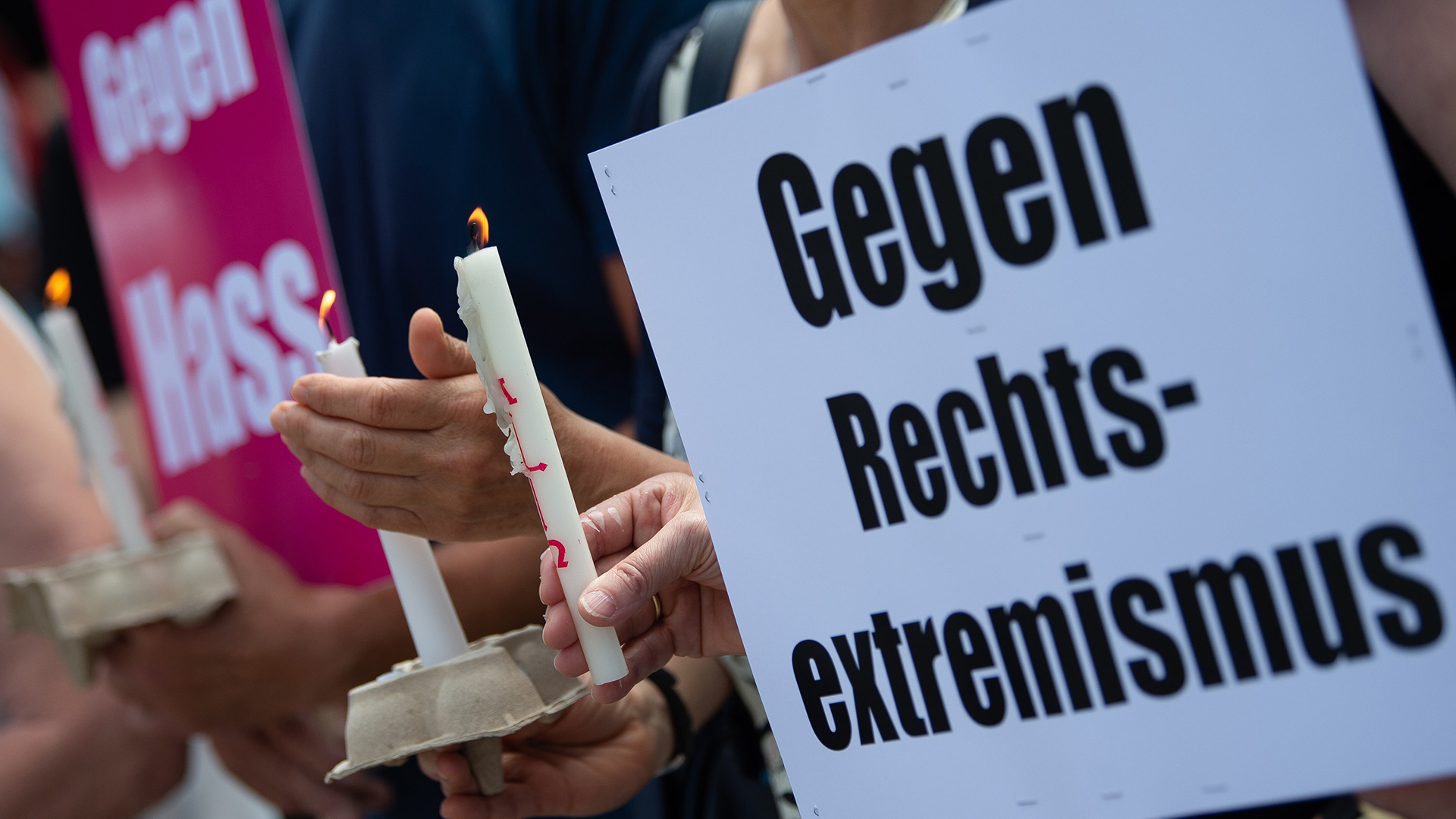 Teilnehmer einer Mahnwache in Wolfhagen anlässlich des Mordes am Kasseler Regierungspräsidenten Walter Lübcke halten Kerzen und Plakate in den Händen. | dpa