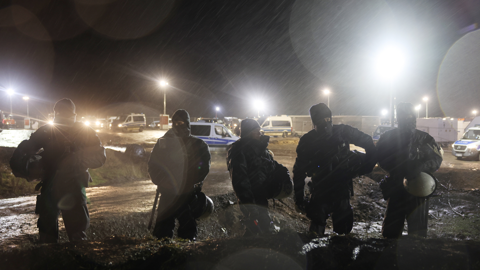 Polizisten stehen am Morgen im Regen am Ortsrand von Lützerath. | dpa