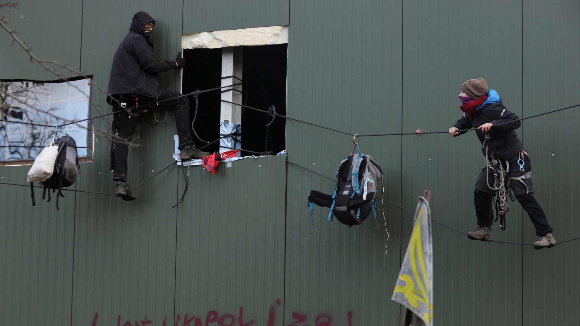 Besetzer des nordrhein-westfälischen Dorfes Lützerath hangeln sich an Seilen an einer Hauswand entlang. | REUTERS