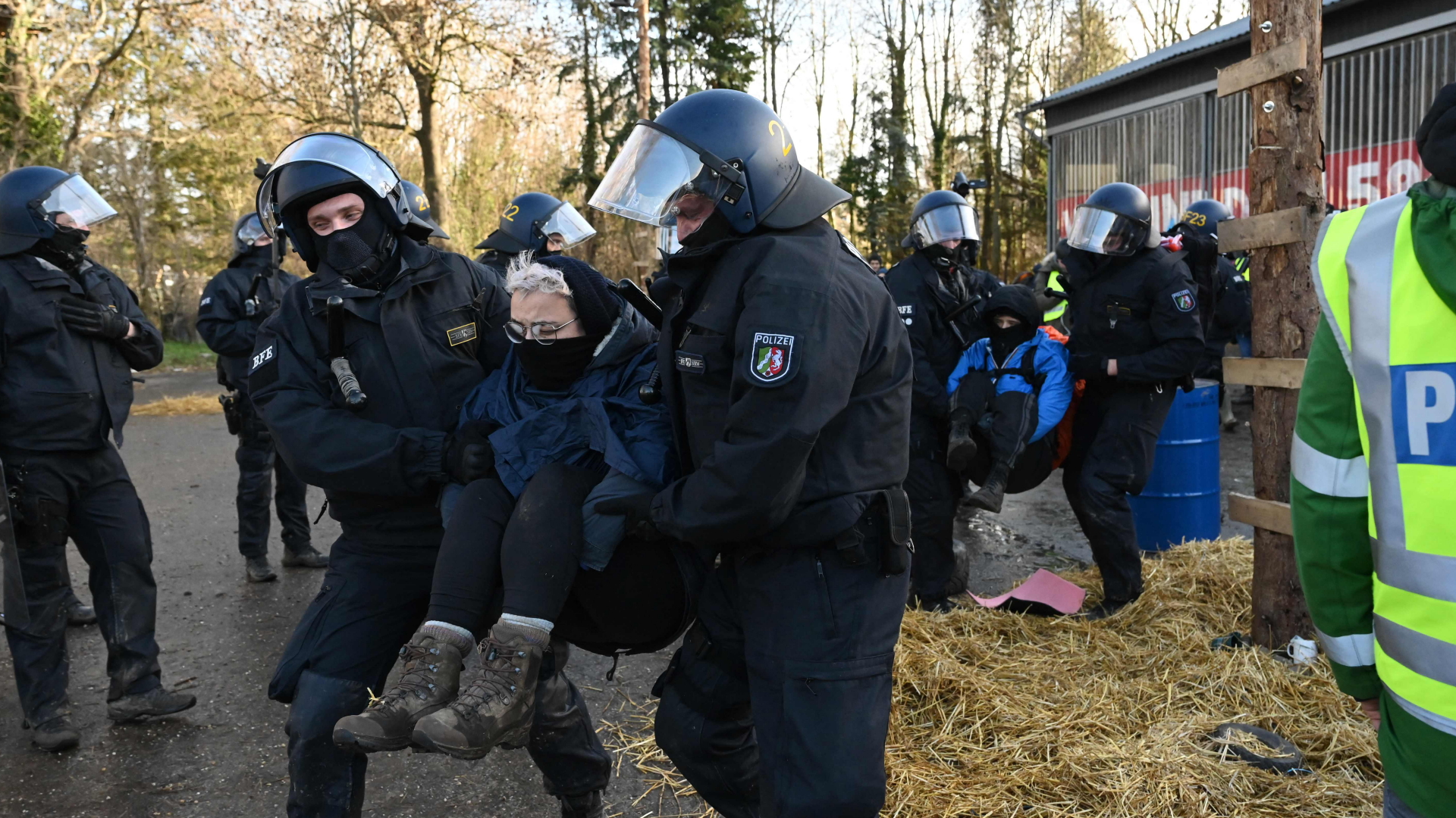 Behelmte Polizisten tragen Protestierende in Lützerath weg. | AFP