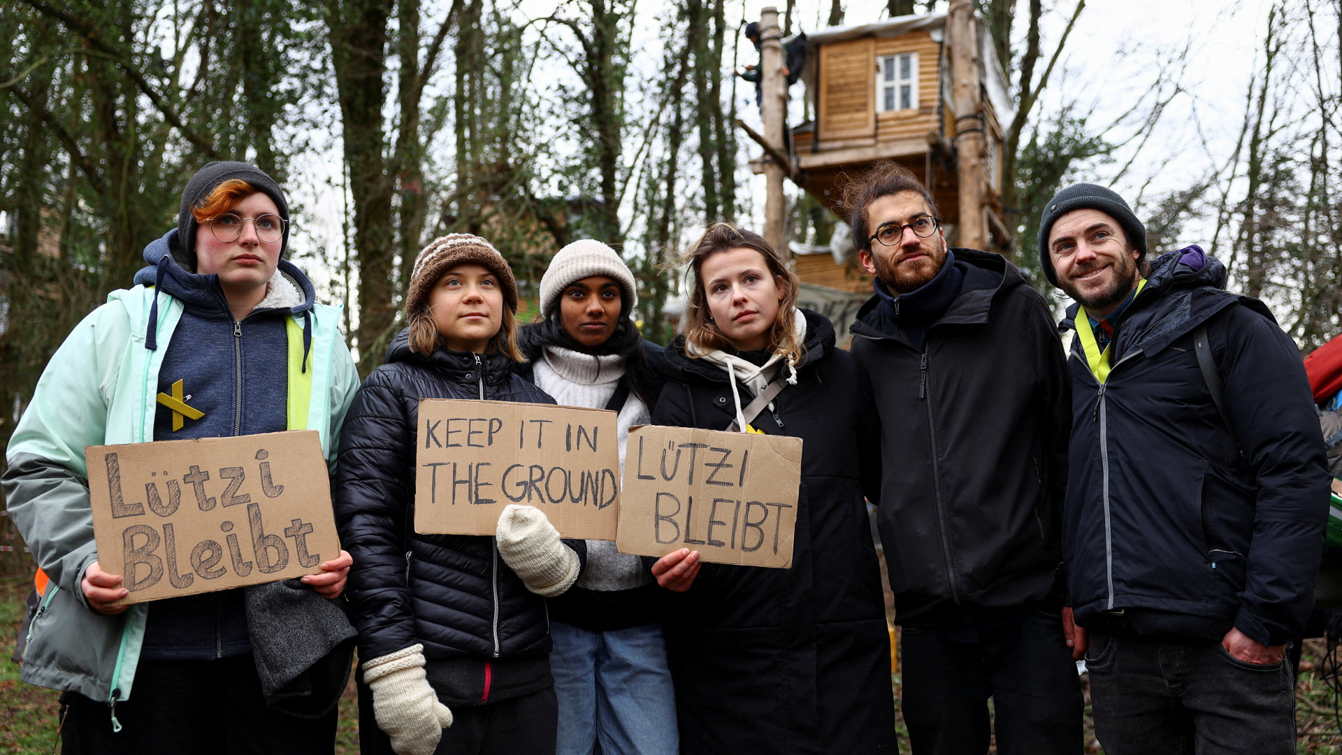 Klimaaktivistinnen, darunter Greta Thunberg (2. v.l.) und Luisa Neubauer (4. v.l.), halten vor einem Baumhaus in Lützerath Protestschilder. | REUTERS
