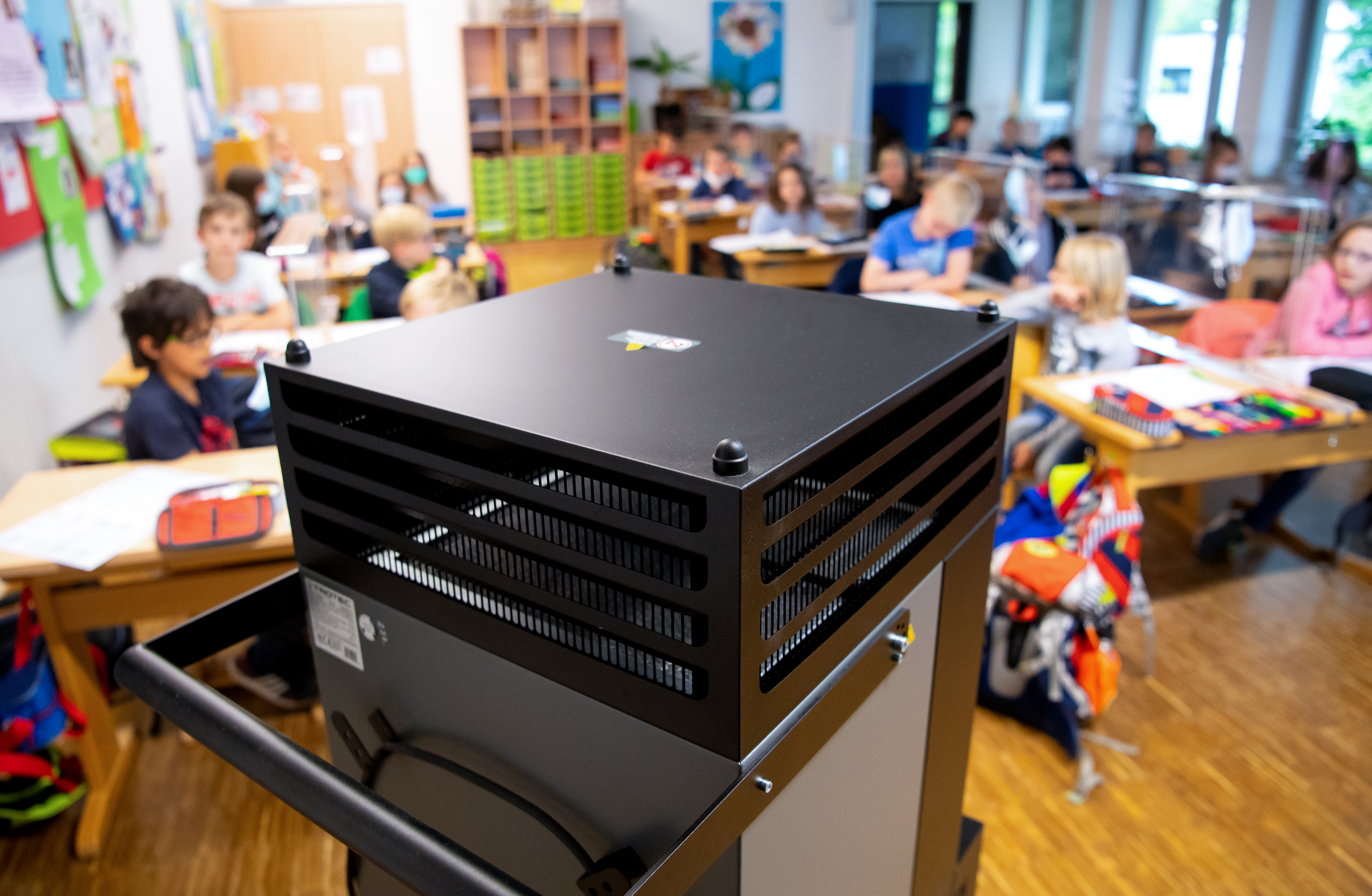 Ein mobiles Luftfiltergerät steht während es Unterrichts in einem Klassenraum | dpa