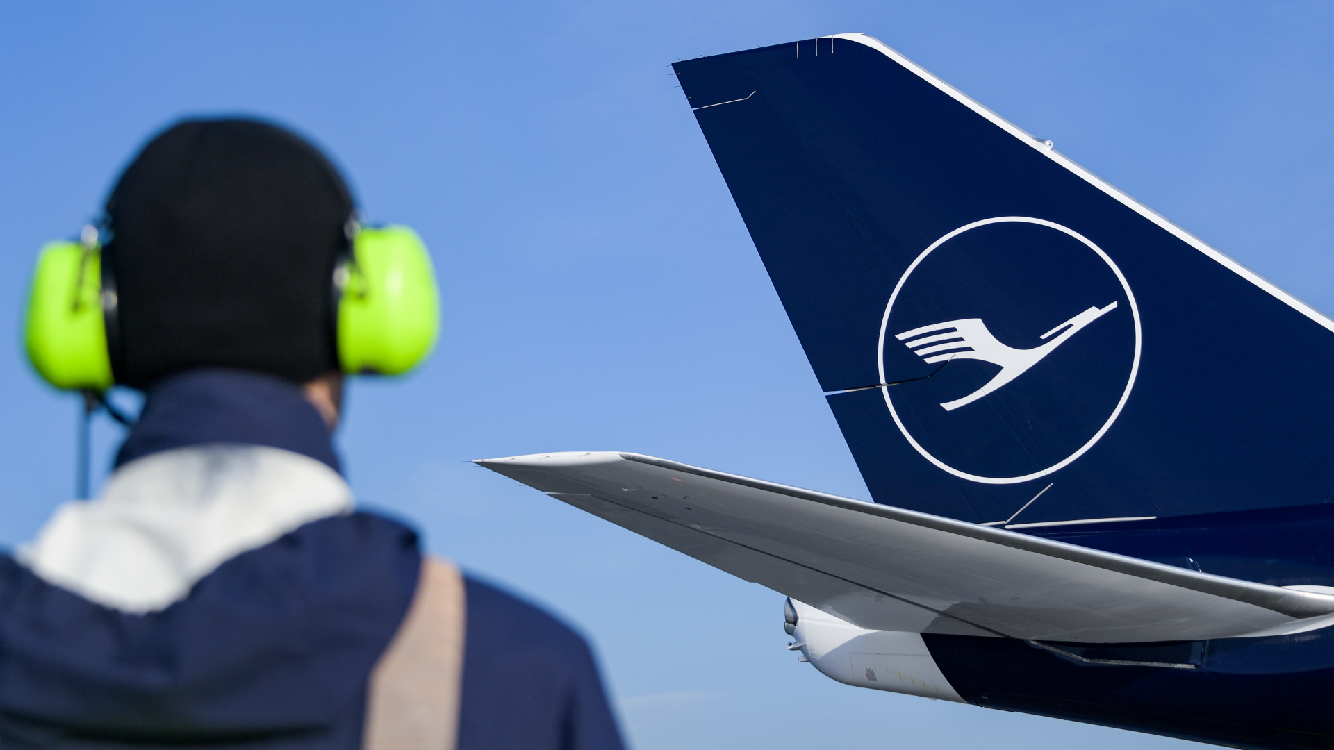 Ein Flughafenmitarbeiter steht vor einem Flugzeug der Lufthansa. | dpa