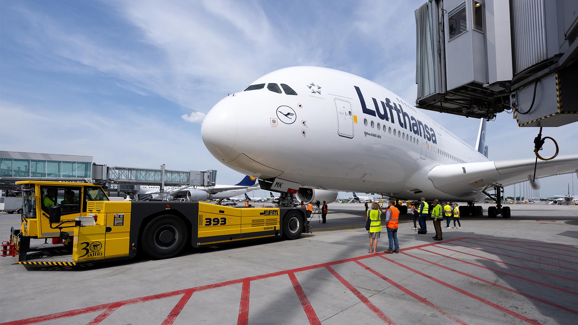 Bodenpersonal vor einem Airbus A380 der Lufthansa auf einem Rollfeld.