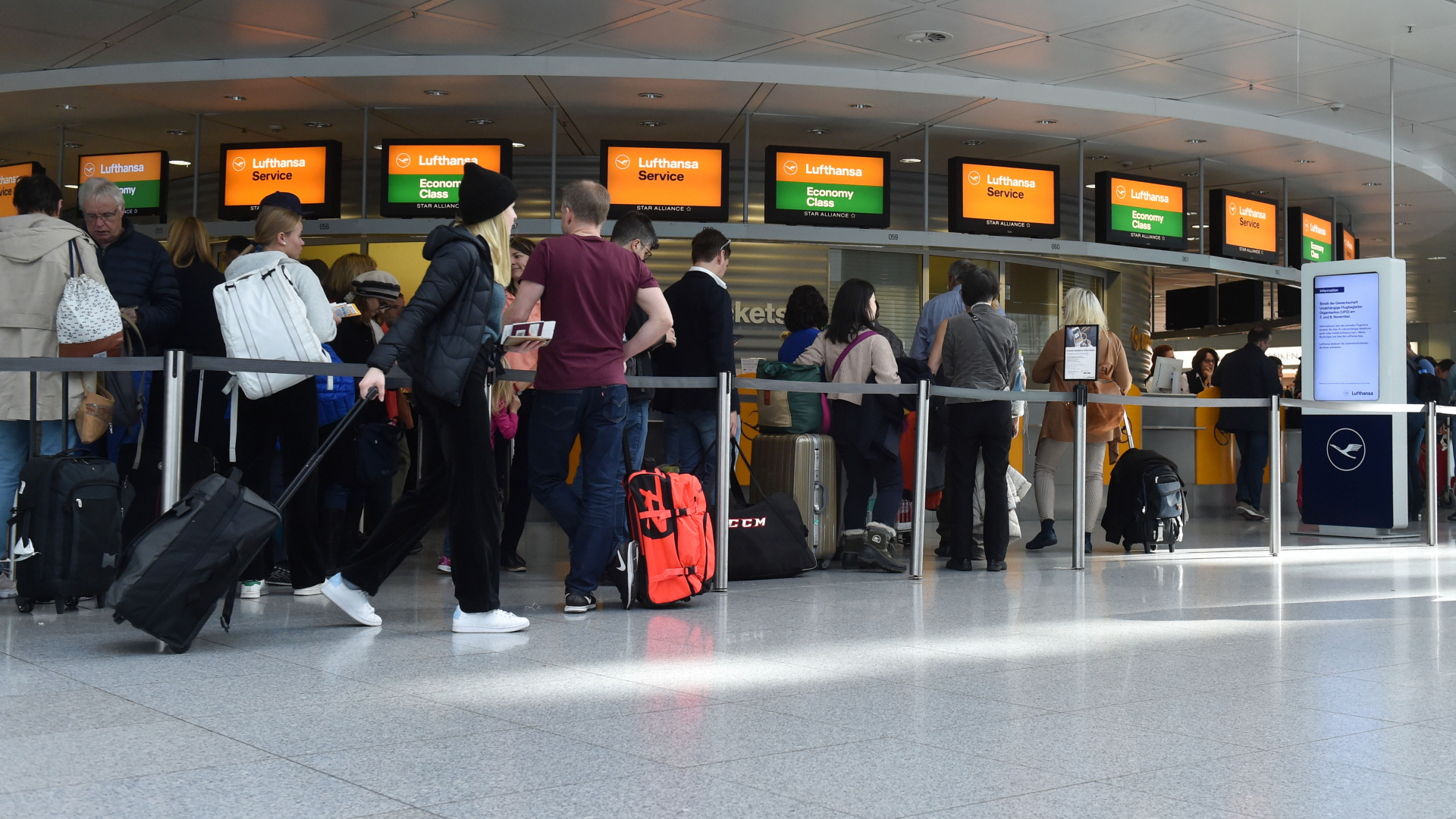 Passagiere stehen an einem Lufthansa Schalter am Flughafen München Schlange. | AFP