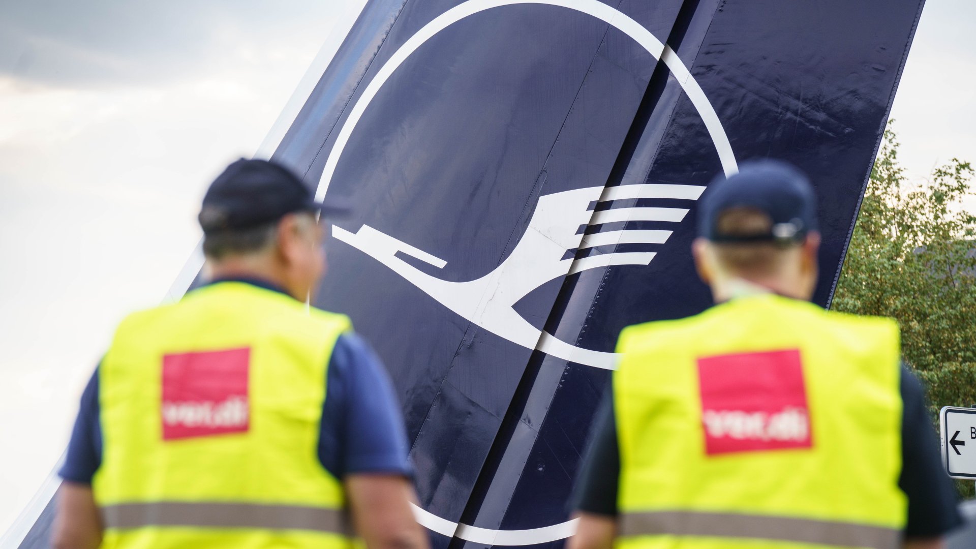 Zwei Lufthansa-Mitarbeiter in ver.di-Warnweste vor einem Flugzeug | dpa