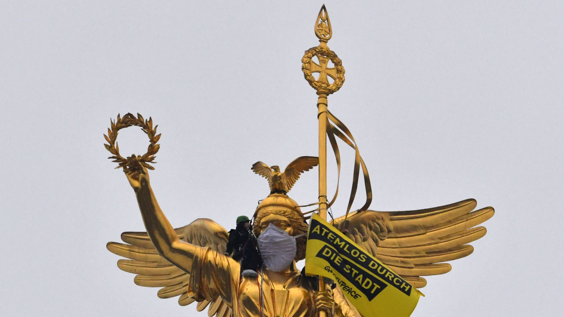 Aktivisten der Umweltschutzorganisation Greenpeace haben der Statue auf der Siegessäule eine Atemschutzmaske übergezogen. | dpa