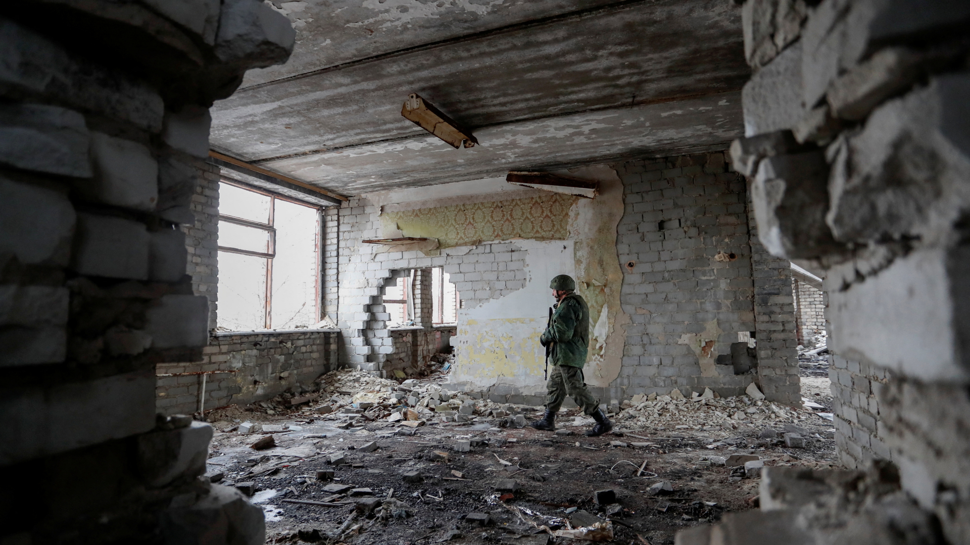 Ein pro-russischer Separatist patrouilliert in einem zerstörten Gebäude nahe der Region Luhansk. | REUTERS
