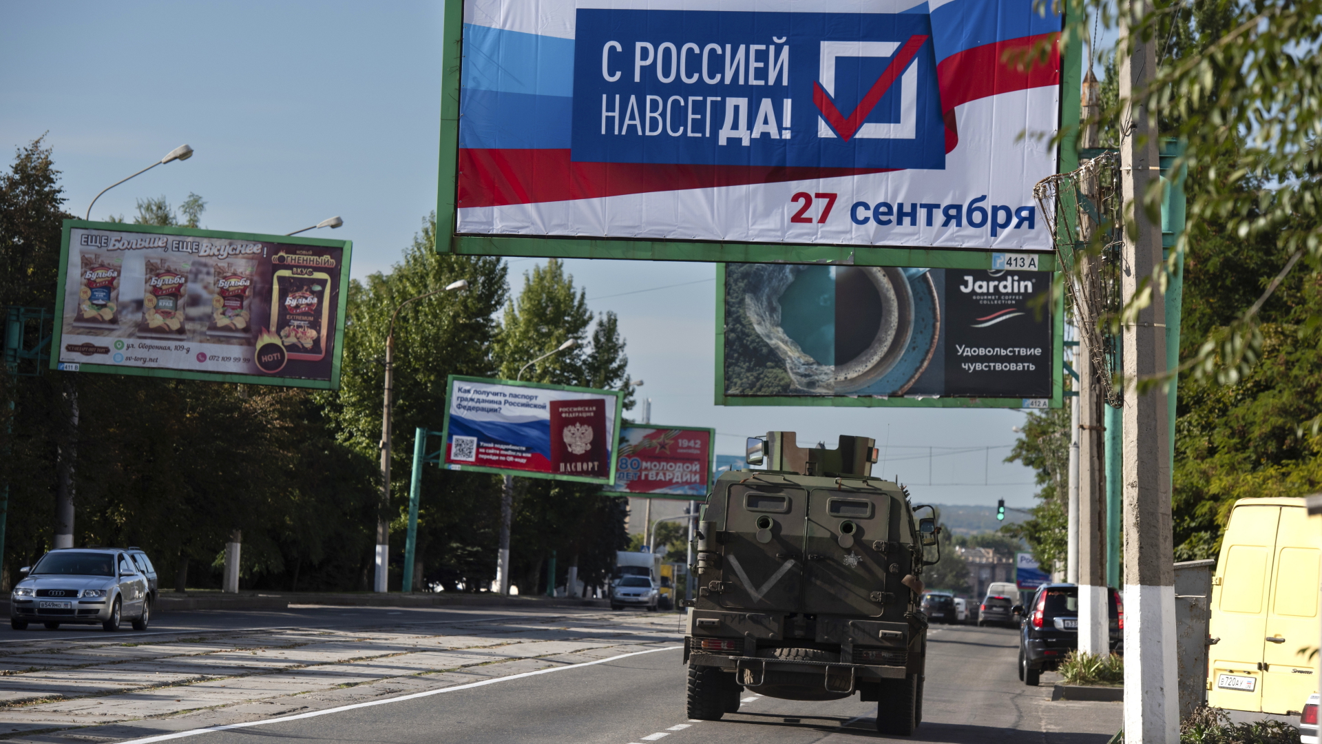 Ein Militärfahrzeug in der von Russland unterstützten und von Separatisten kontrollierten Volksrepublik Luhansk in der Ostukraine fährt an einem Plakat mit der Aufschrift "Für immer mit Russland, 27. September" vorbei. | dpa