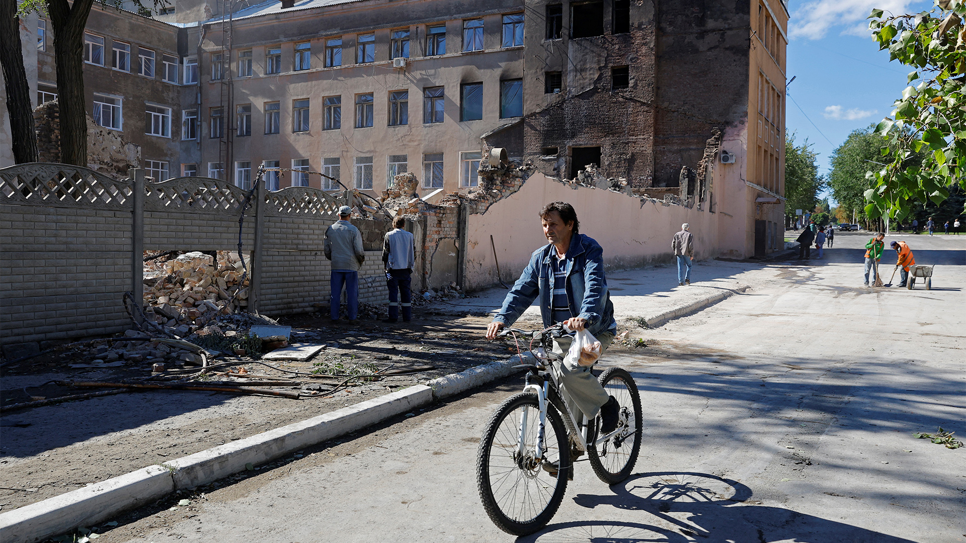 Ein Mann fährt mit seinem Fahrrad an zerstörten Gebäuden in Stachanow (Luhansk) vorbei. | REUTERS