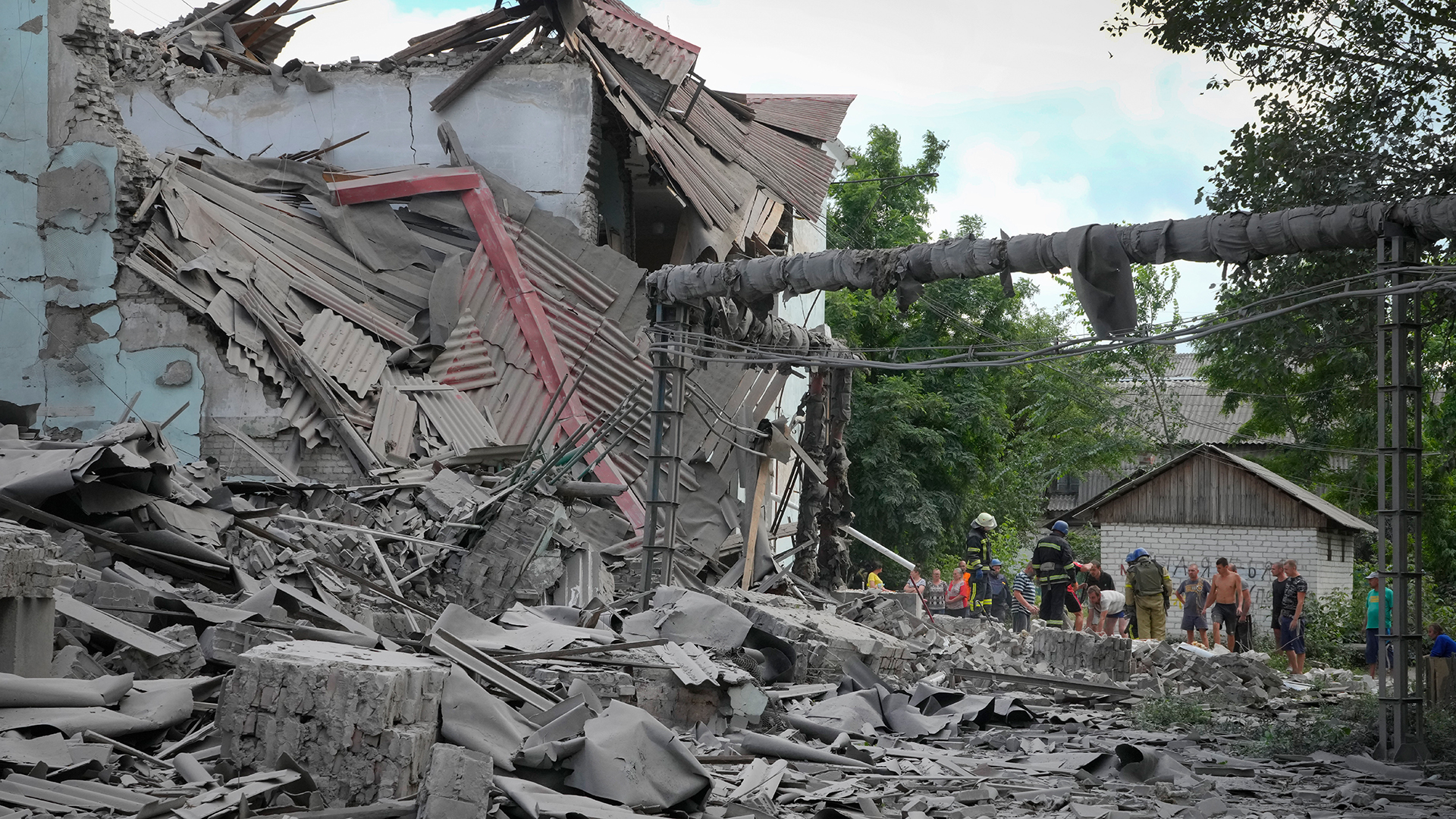 Rettungskräfte und Anwohner vor den Trümmern eines Gebäudes in Lyssytschansk. | dpa