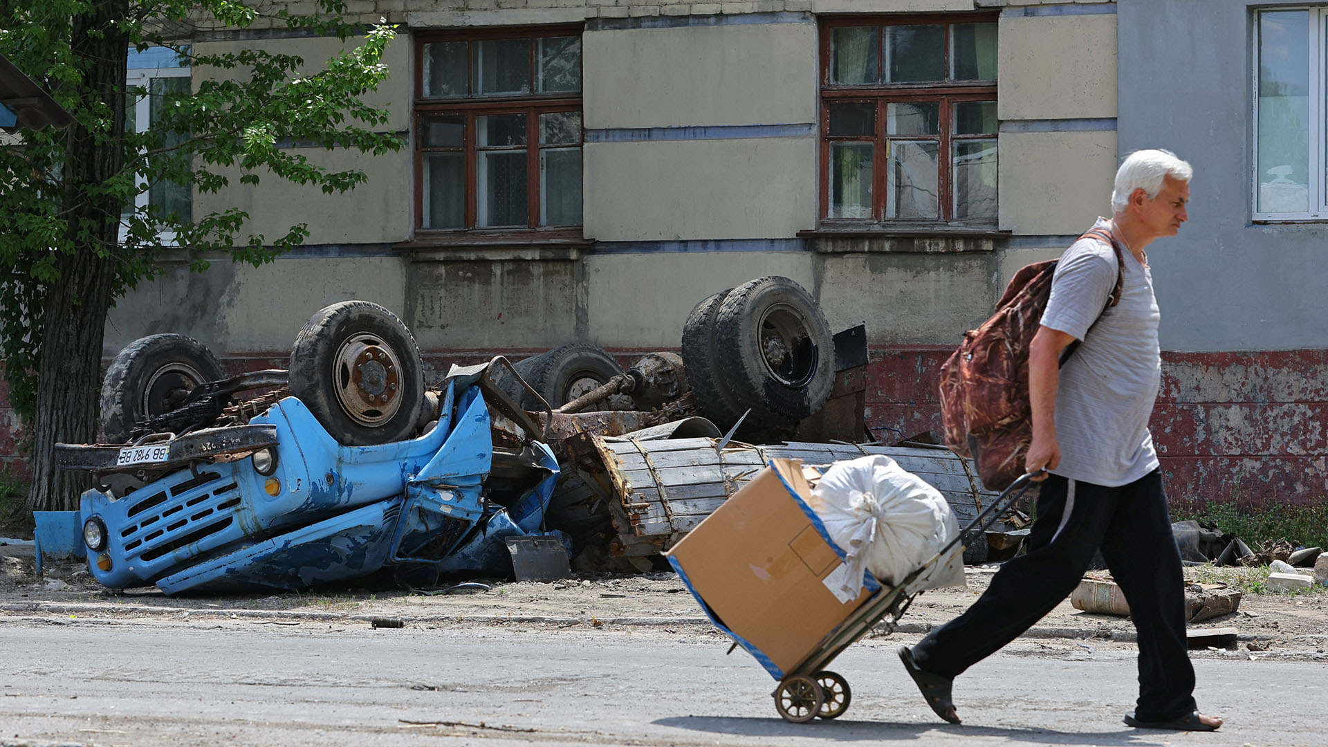 Ein Anwohner geht an einem zerstörten Fahrzeug in der Stadt Lyssytschansk vrobei. | REUTERS