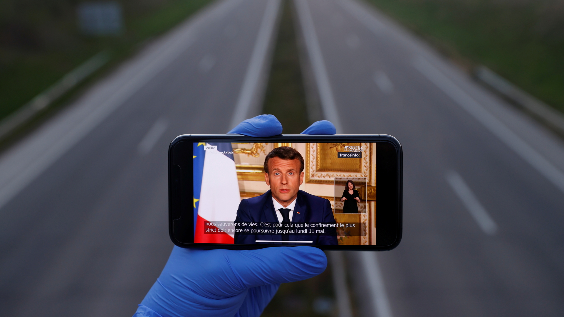 Handy mit dem Bild von Macron vor leerer Straße | REUTERS