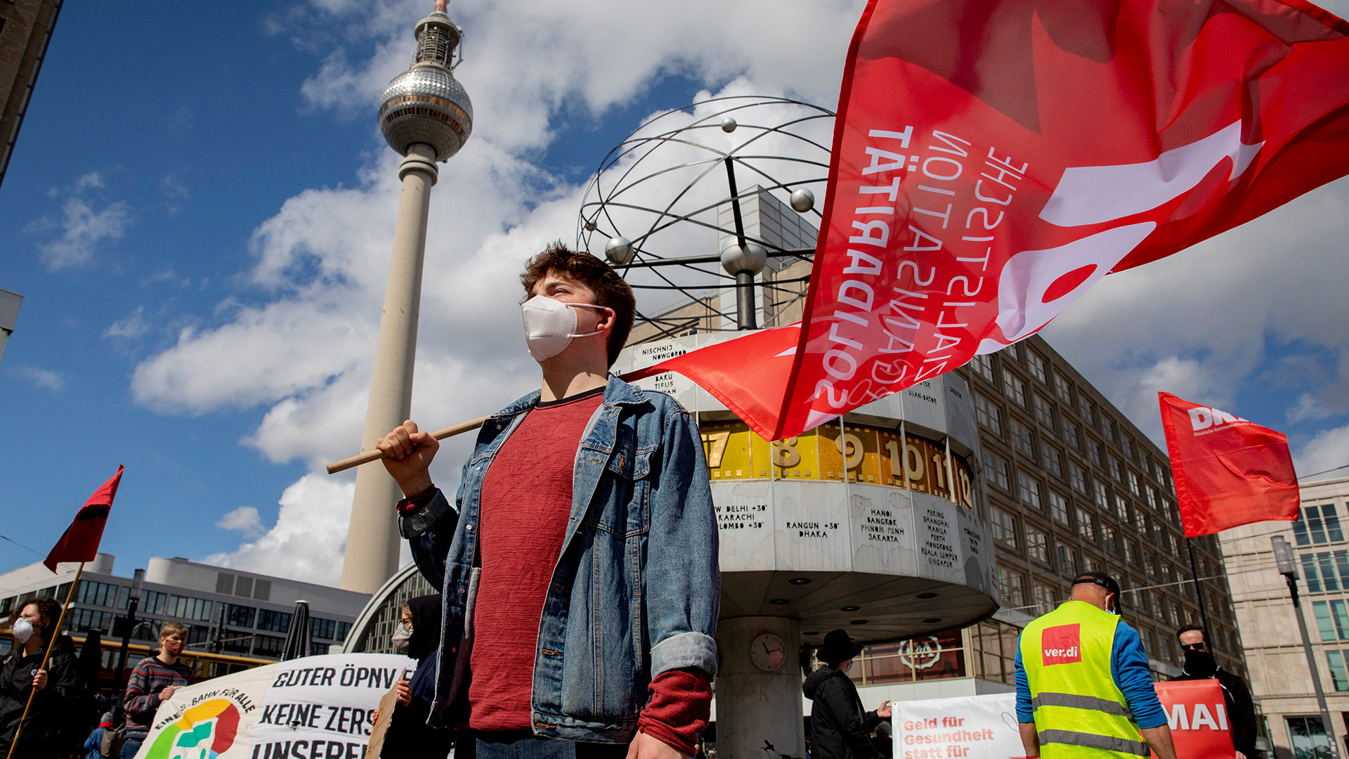 Ein Mann mit Atemschutzmaske steht bei einer Kundgebung verschiedener gewerkschaftlicher Aktiver am Alexanderplatz unter der Weltzeituhr. | dpa