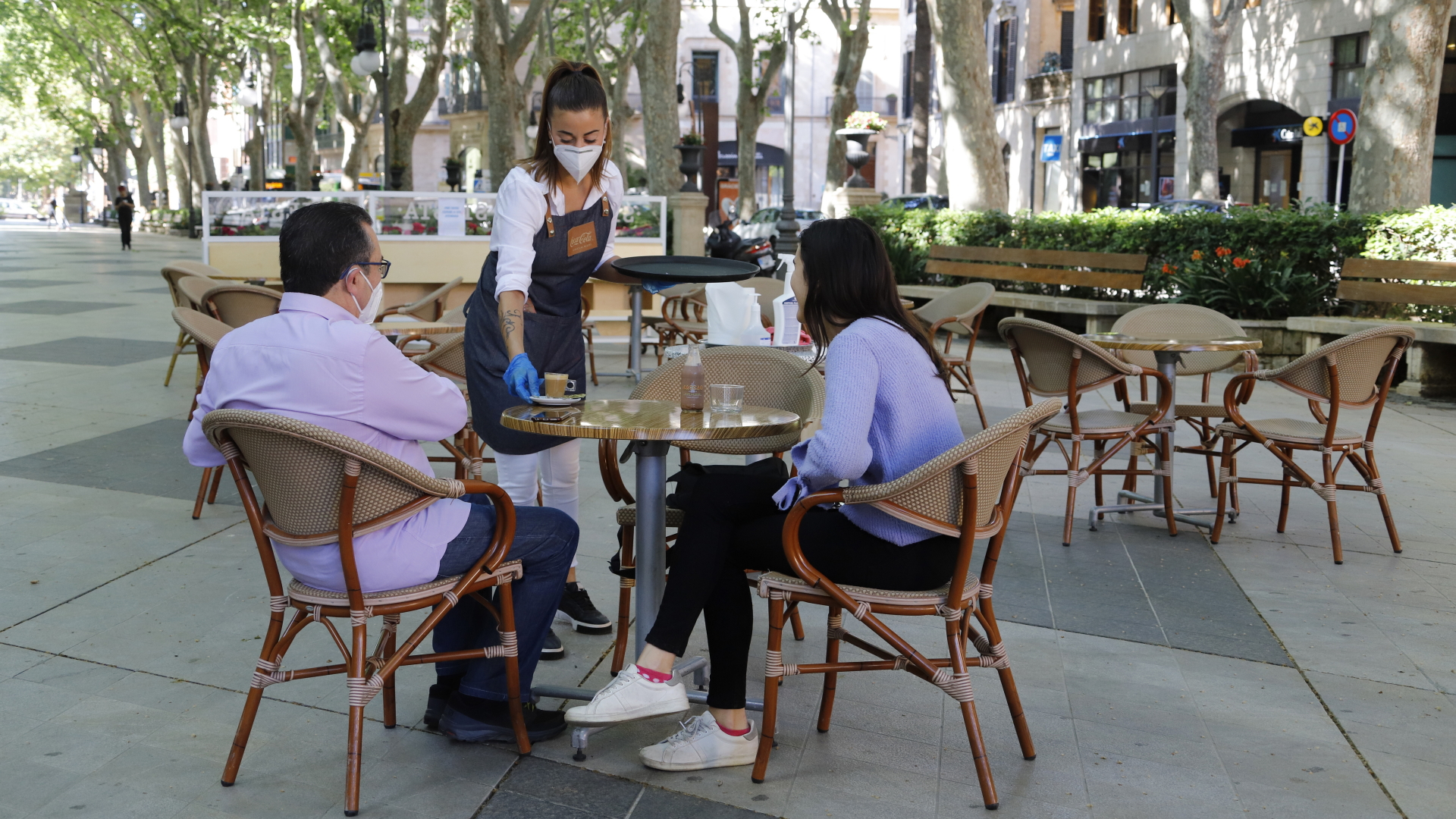 Am Tag der Wiedereröffnung serviert eine Kellnerin zwei Gästen auf der Terrasse einer Bar in Palma auf Mallorca einen Kaffee.