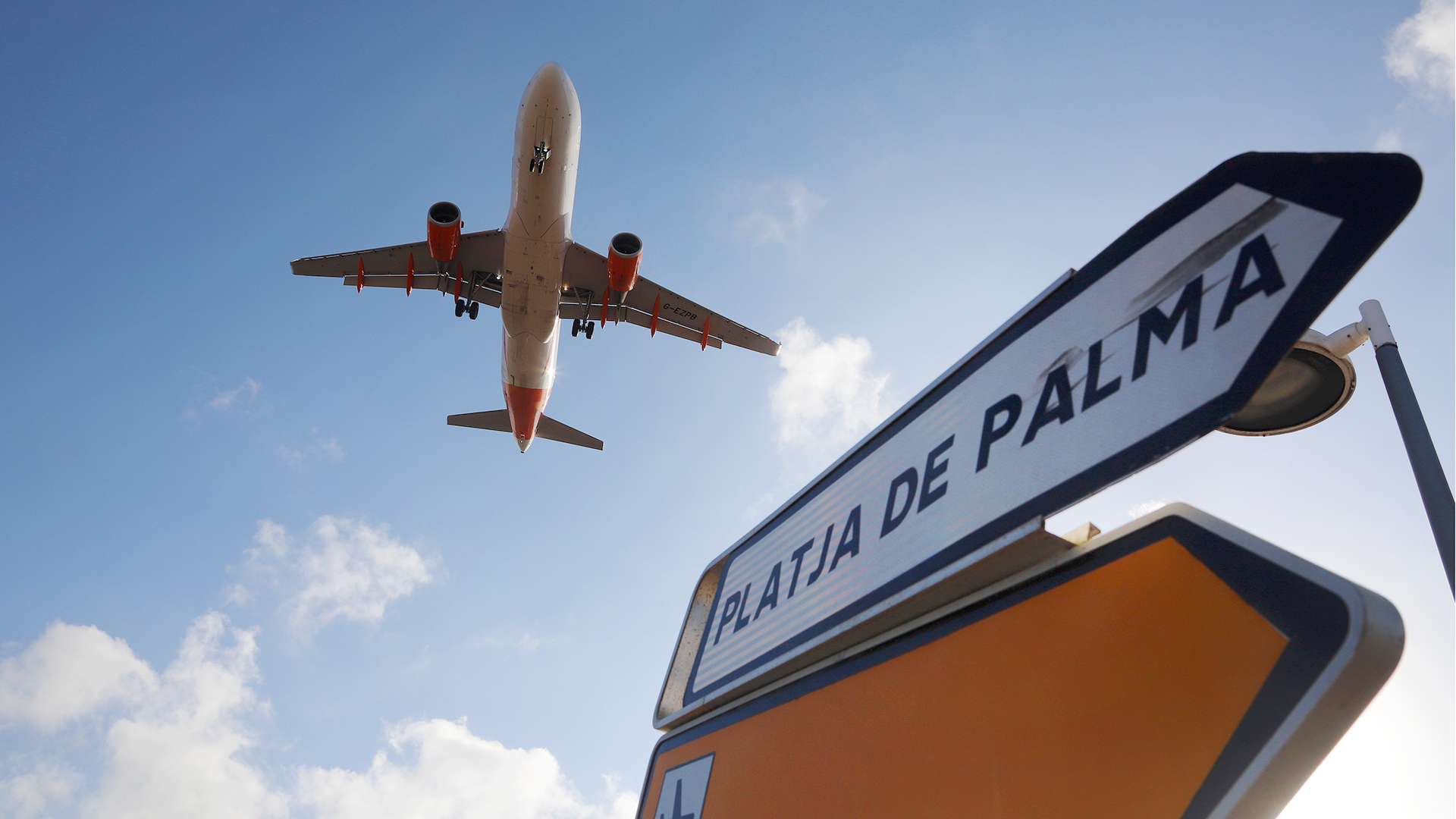Ein Flugzeug überfliegt bei der Landung auf Mallorca ein Schild, das die Richtung nach Playa de Palma anzeigt. | dpa