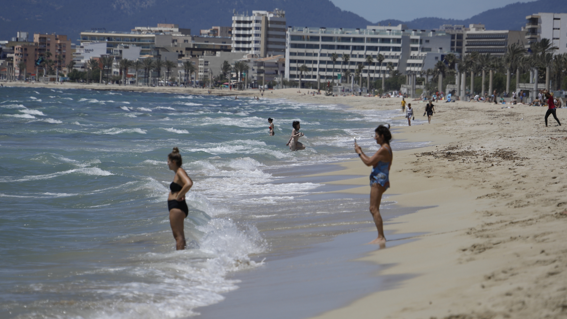 Menschen gehen am Strand von Arenal auf Mallorca schwimmen. | dpa
