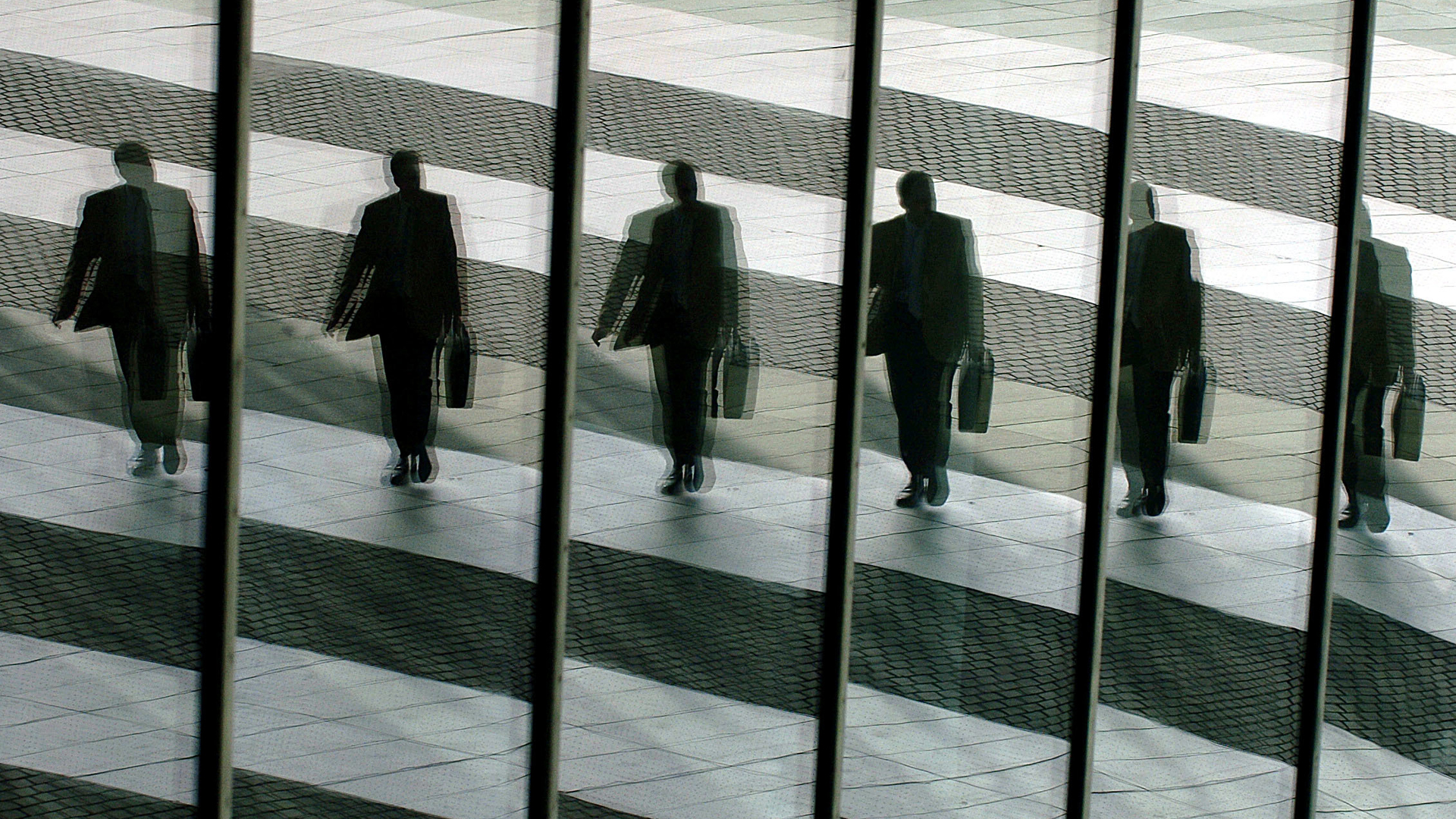 Viele Manner im Anzug mit Koffer spiegeln sich in Scheiben. | picture alliance / dpa