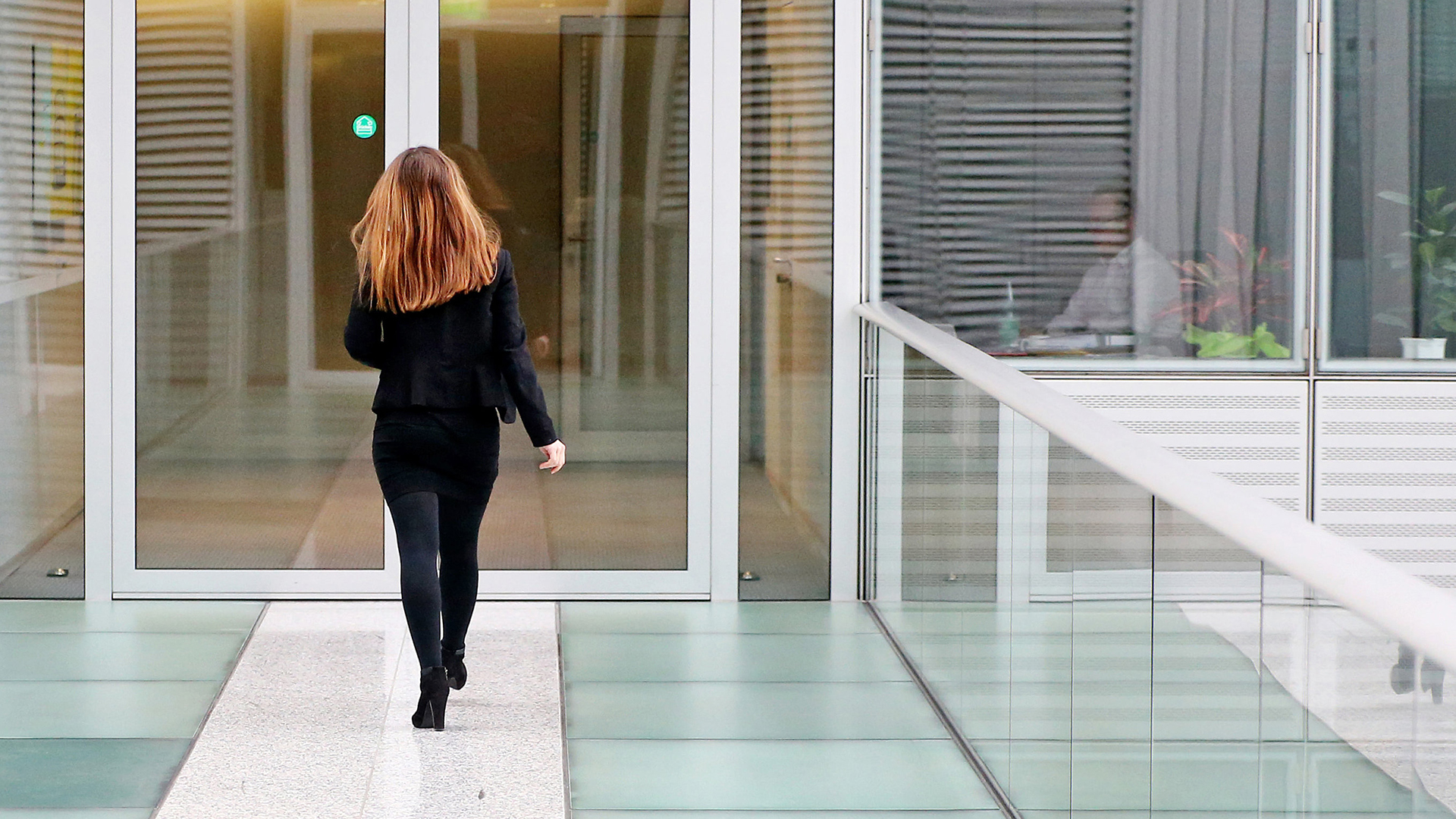 Eine Geschäftsfrau geht einen Gang in einer Konzernzentrale entlang | dpa