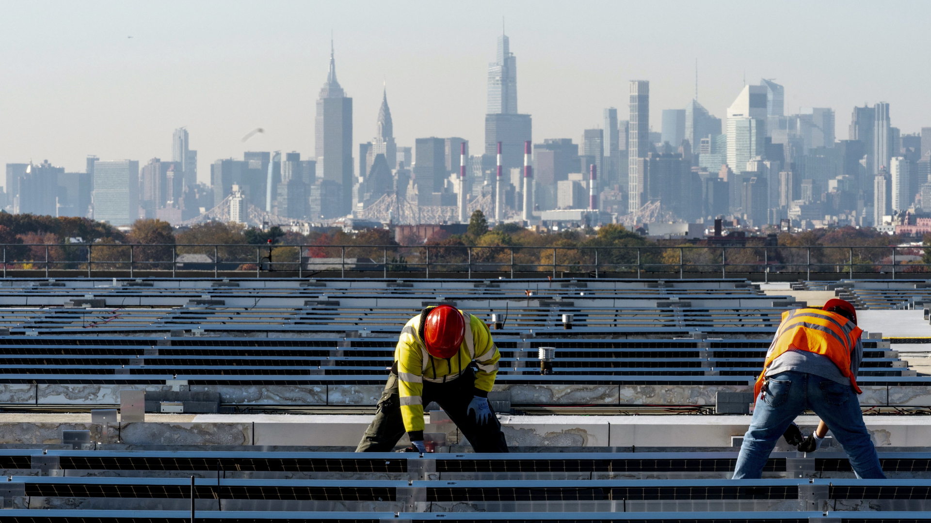  Elektrikern installieren vor der Skyline von Manhattan im New Yorker Stadtteil Queens Solarmodule auf der Garage von Terminal B am Flughafen LaGuardia. | AP