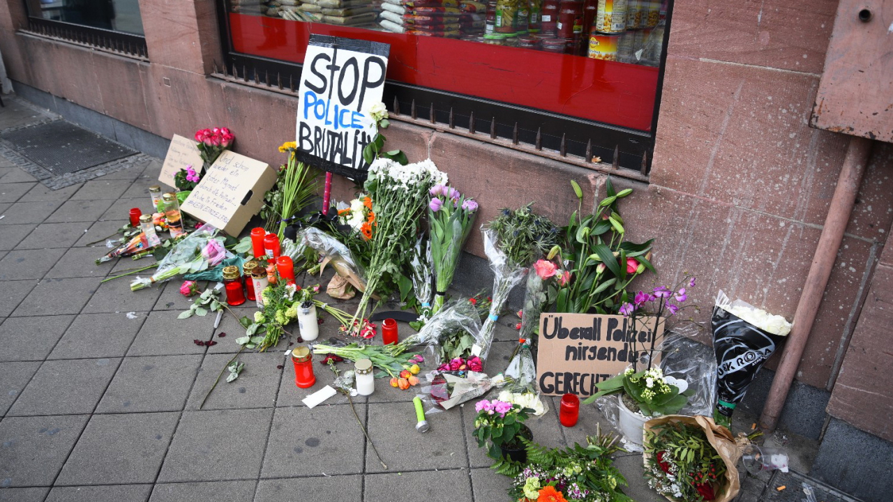 Blumen, Kerzen und Schilder liegen und stehen an dem Ort, an dem am Montag (02.05.2022) ein Mann nach einer Polizeikontrolle gestorben ist.  | dpa