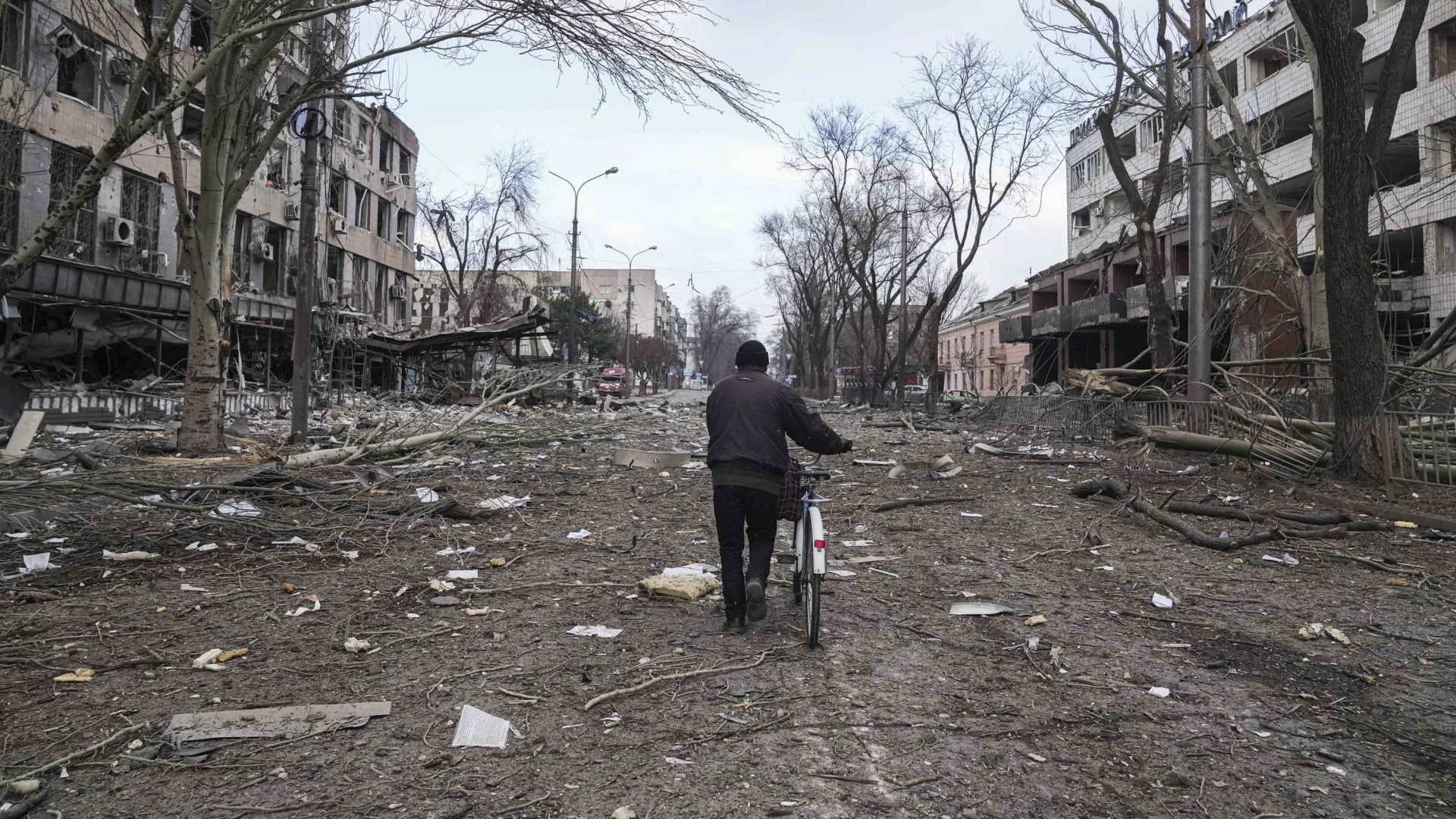 Ein Mann geht mit seinem Fahrrad durch eine zerstörte Straße im ukrainischen Mariupol | AP